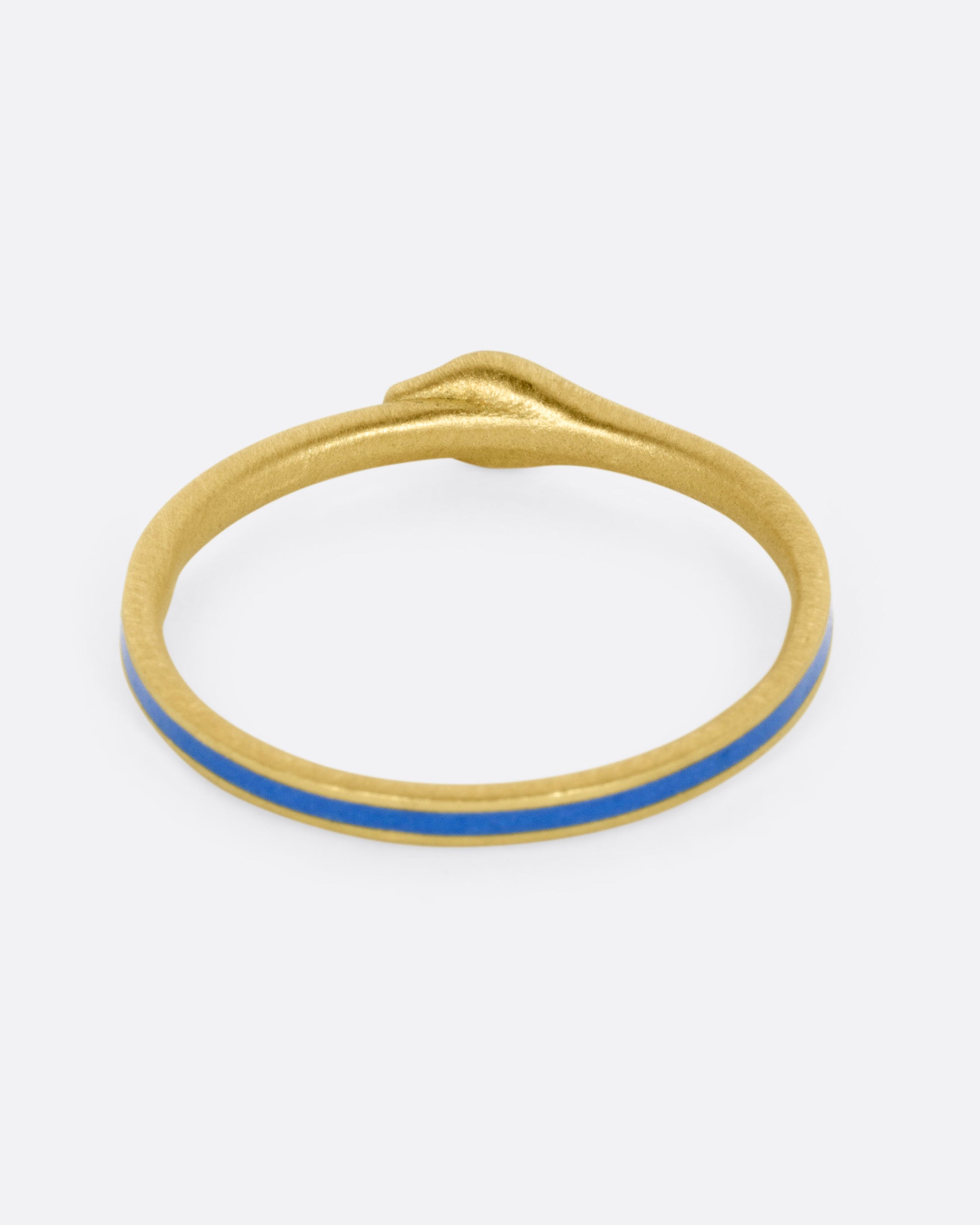 A yellow gold ouroboros ring with diamond eyes and blue enamel, shown from the back