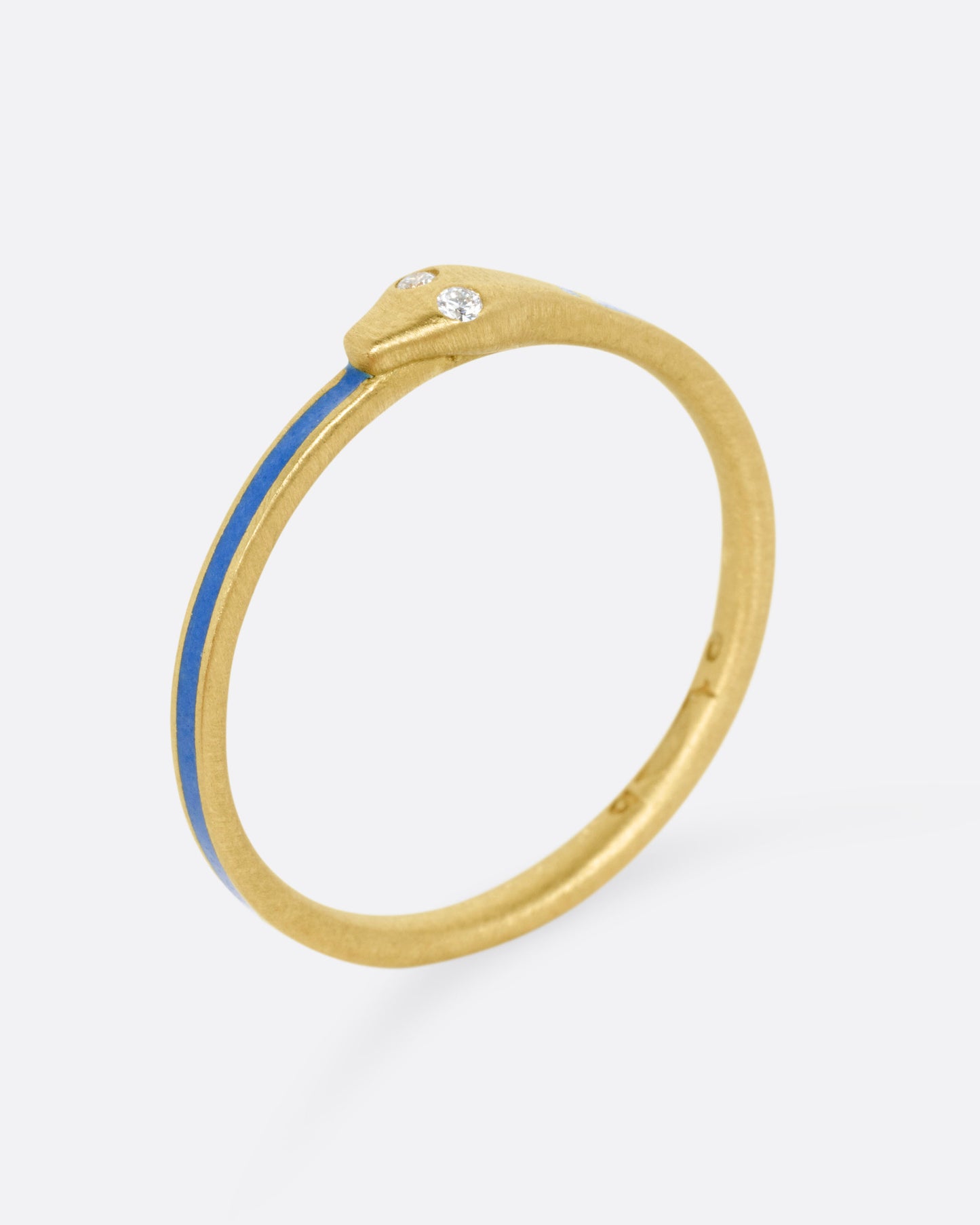 A yellow gold ouroboros ring with diamond eyes and blue enamel, shown standing up from the side. 