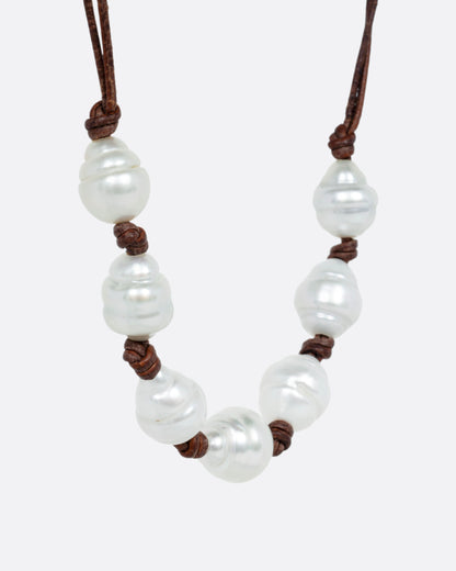 A necklace with a hand knotted leather cord and eight South Sea pearls, shown from the side.