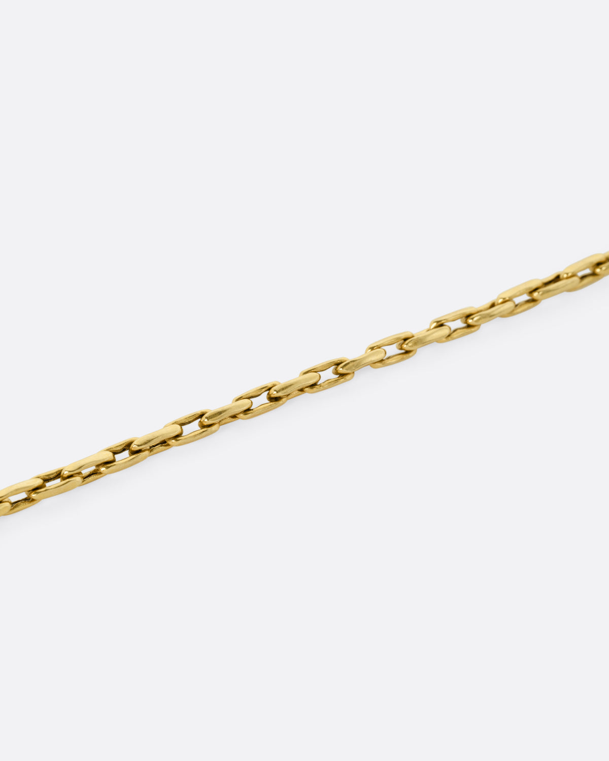 A close up of a A yellow gold box chain with elongated links.