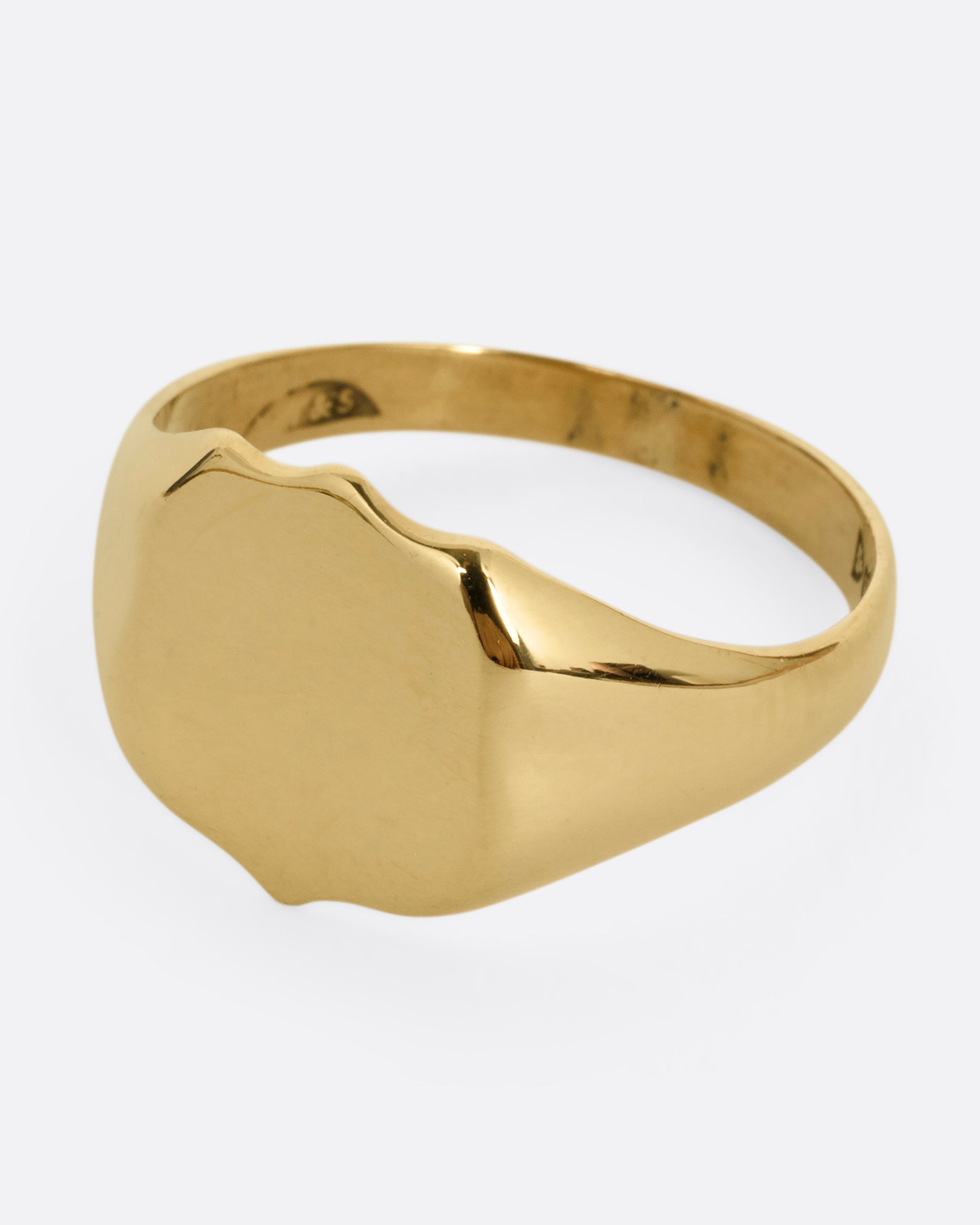 A yellow gold shield shaped signet ring. Shown from the side.