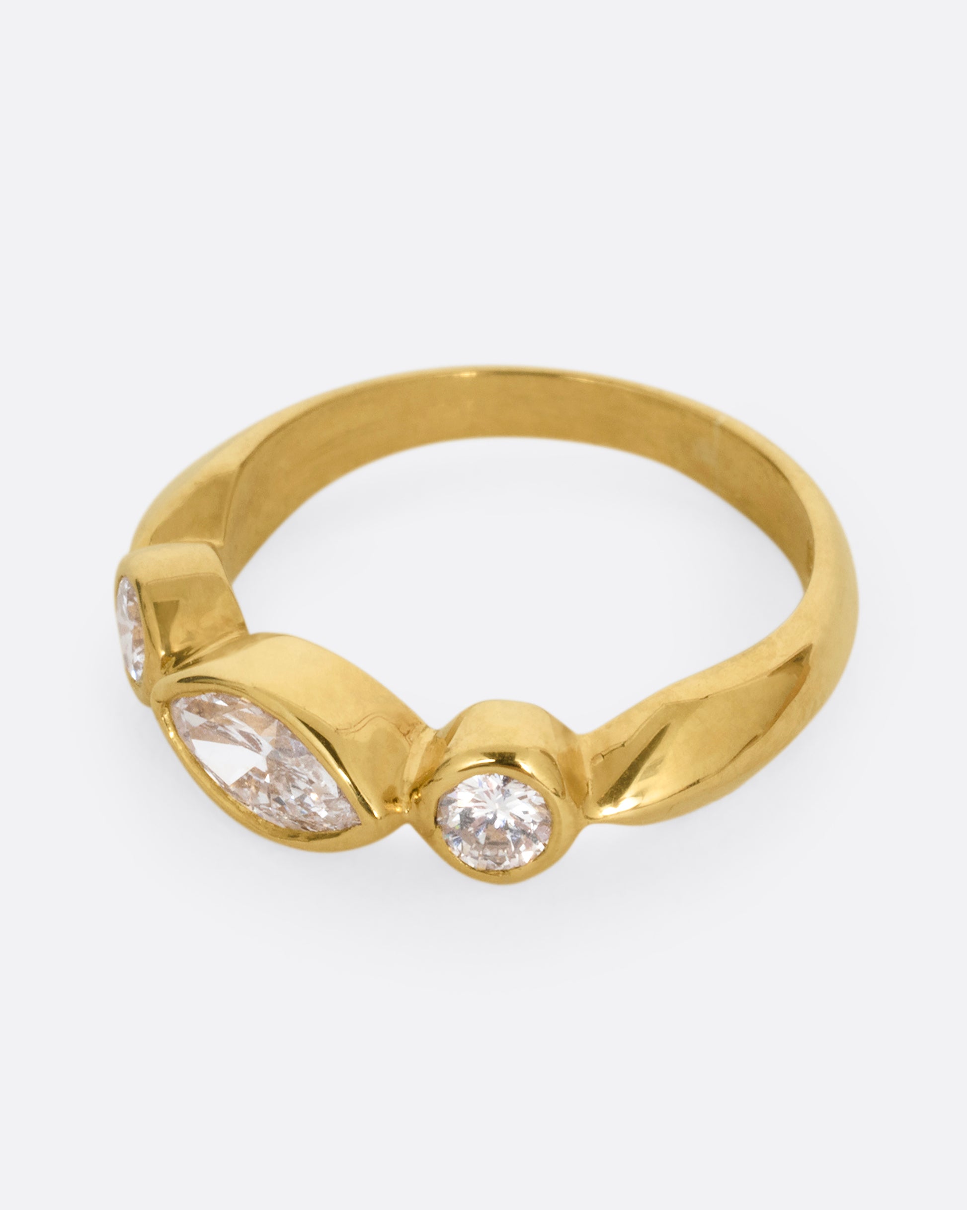 A yellow gold ring with three diamonds shown from the side.