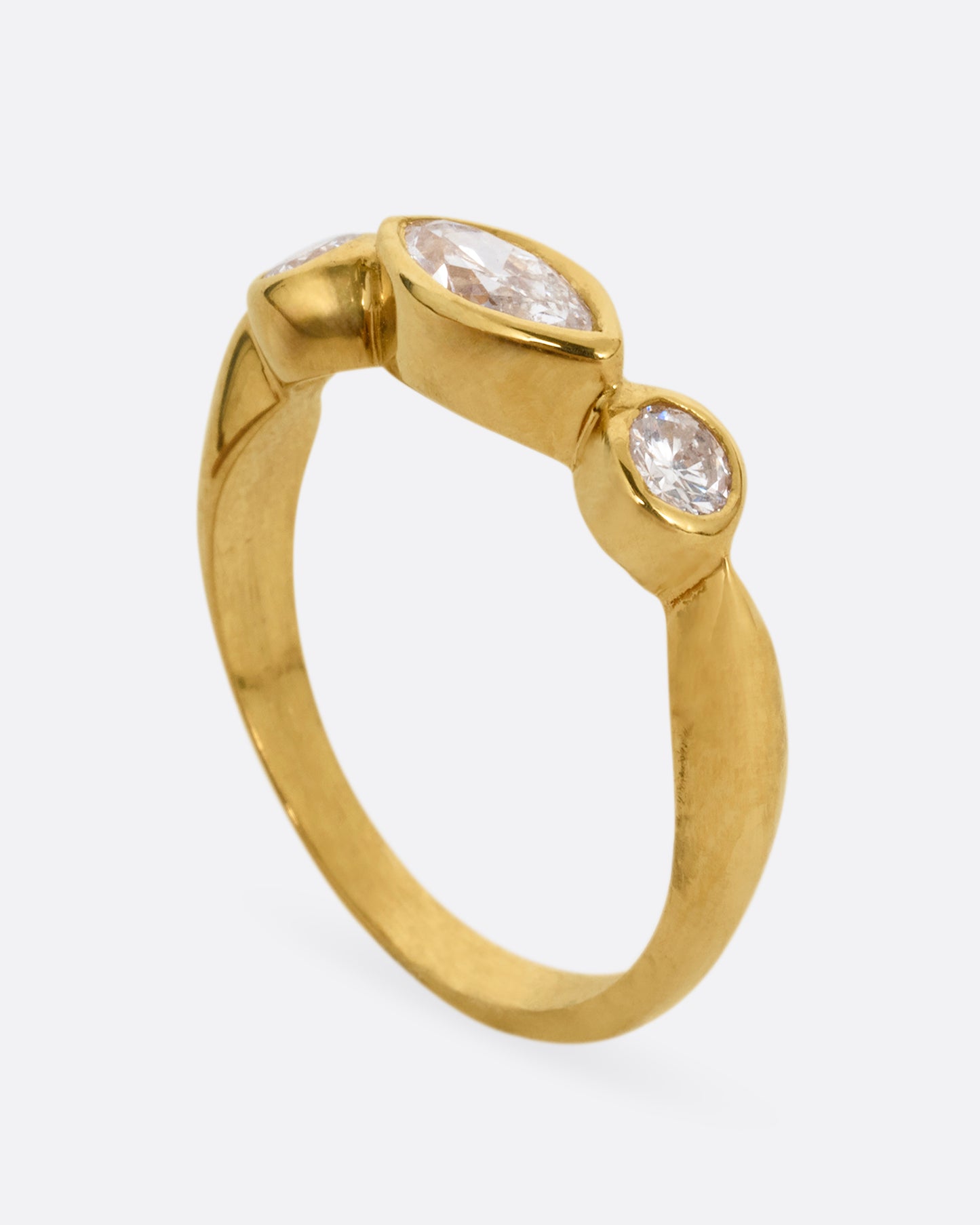 A yellow gold ring with three diamonds shown standing up from the side.