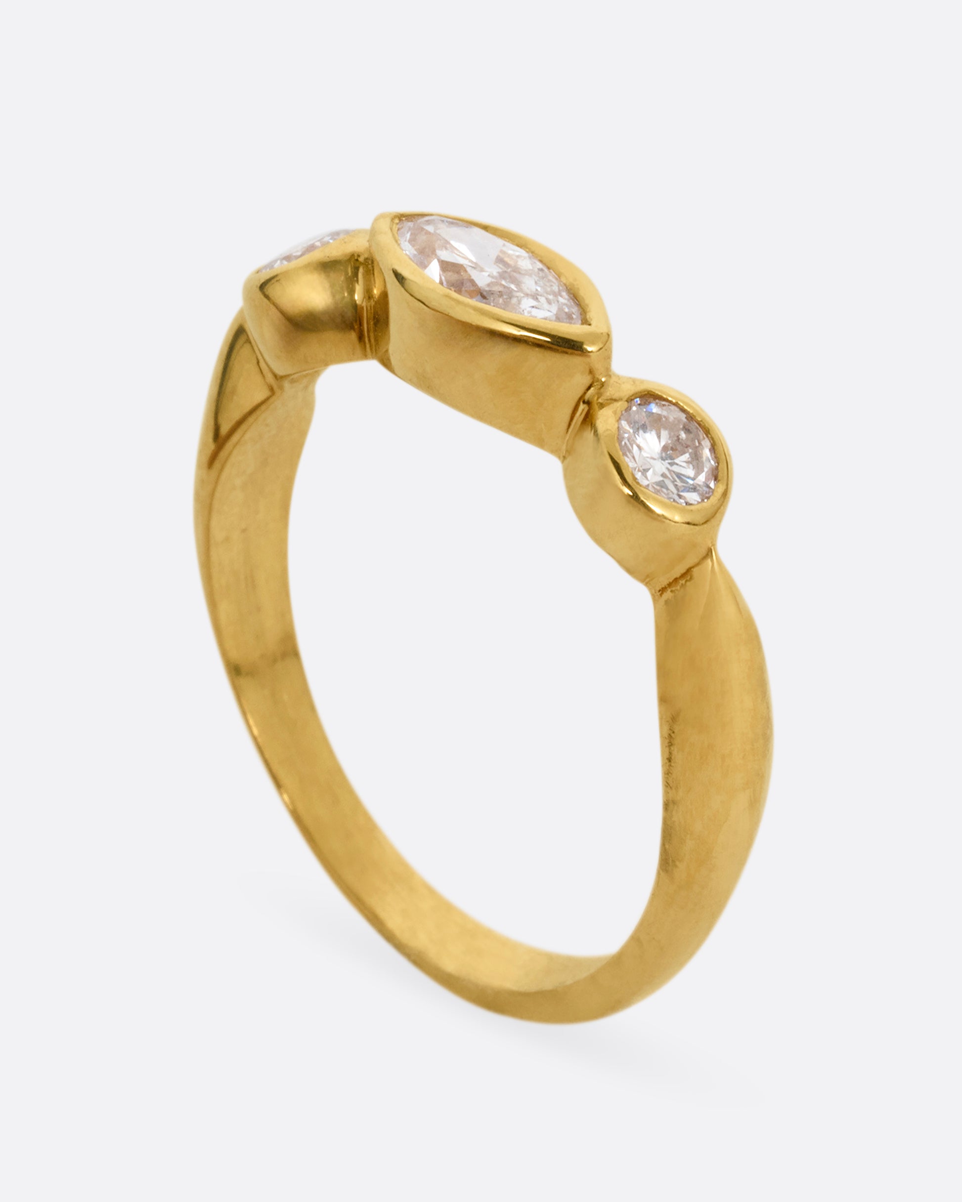 A yellow gold ring with three diamonds shown standing up from the side.