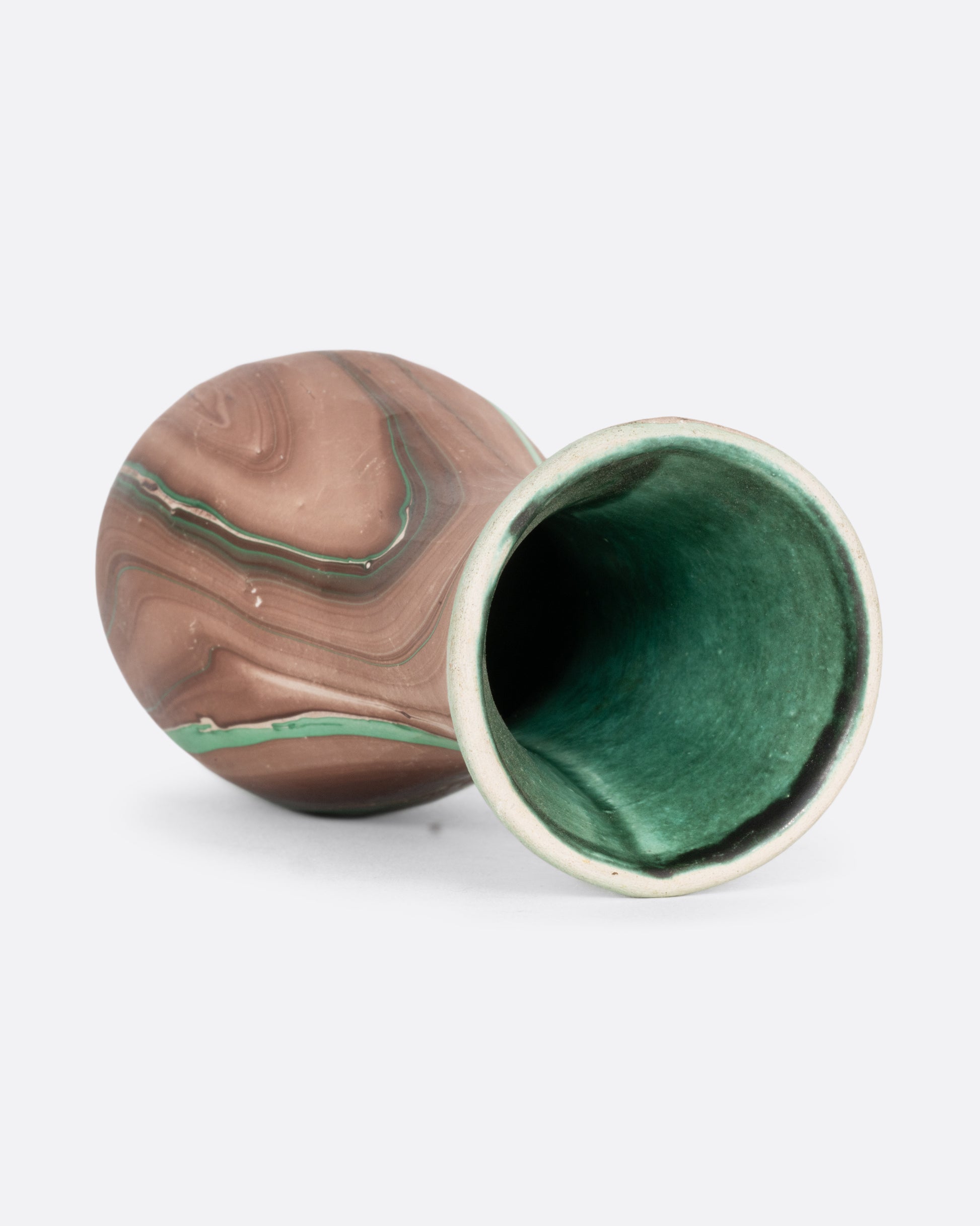 A green and brown swirled vase. Shown lying on its side from the top.