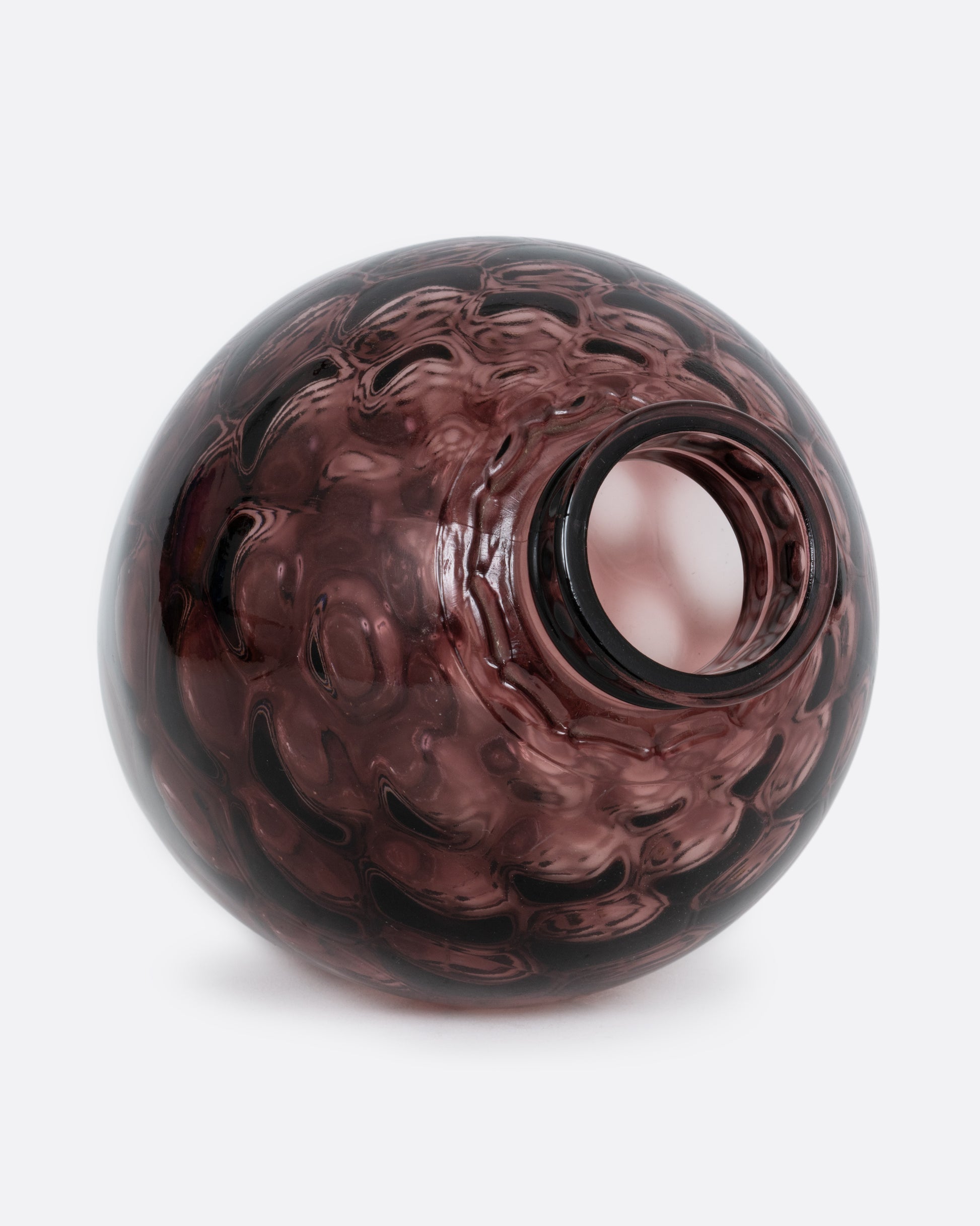 A purple glass vase with a smooth exterior and honeycomb texture interior. Shown lying on its side from the top.