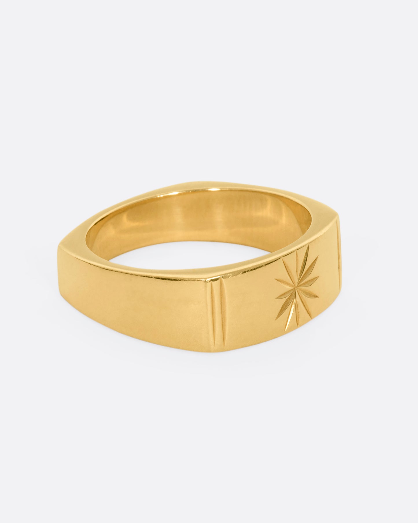 A yellow gold squared band with a star etching on the front. View from the side.