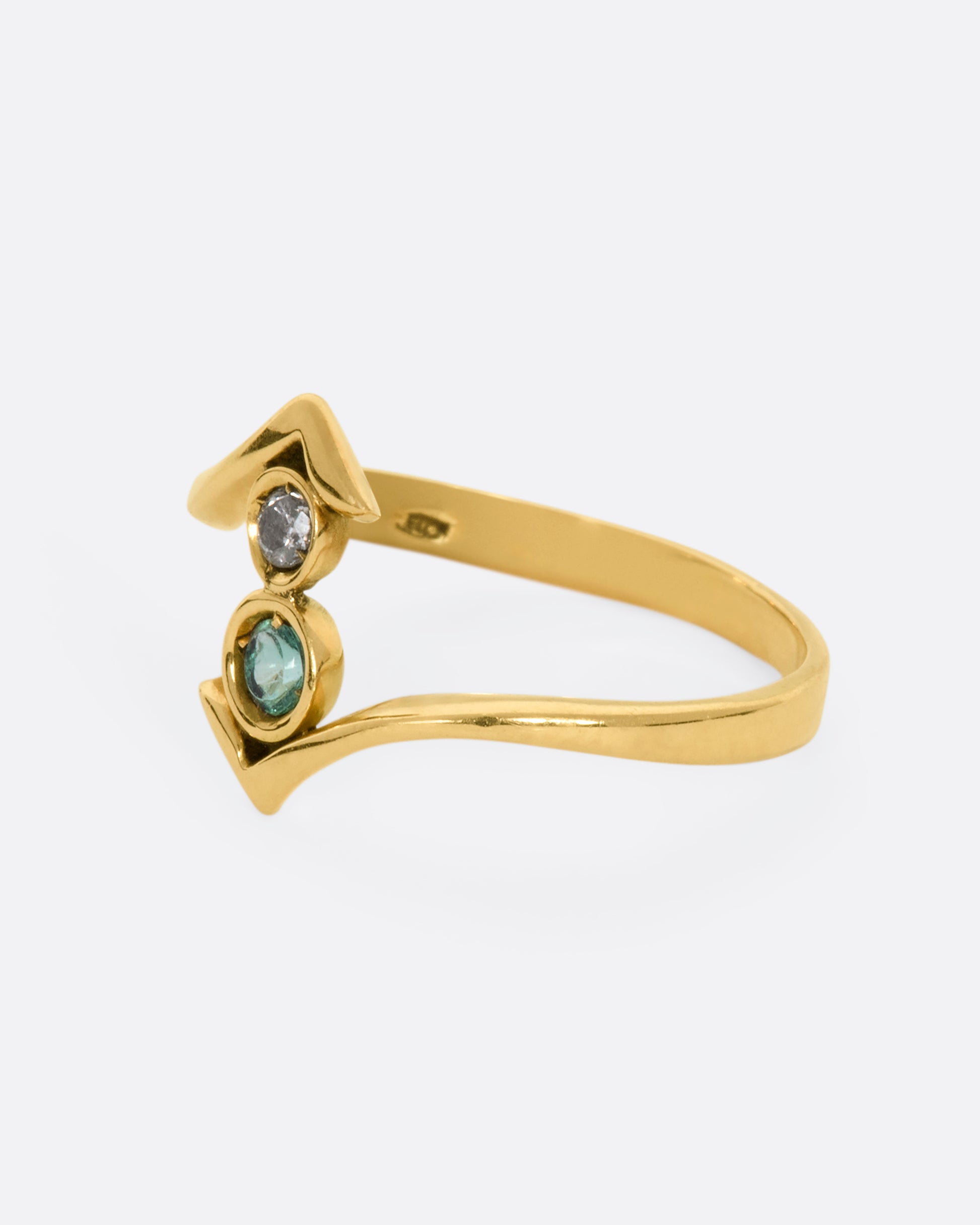 A yellow gold wrap ring with a round diamond and emerald. View from the alternate side.