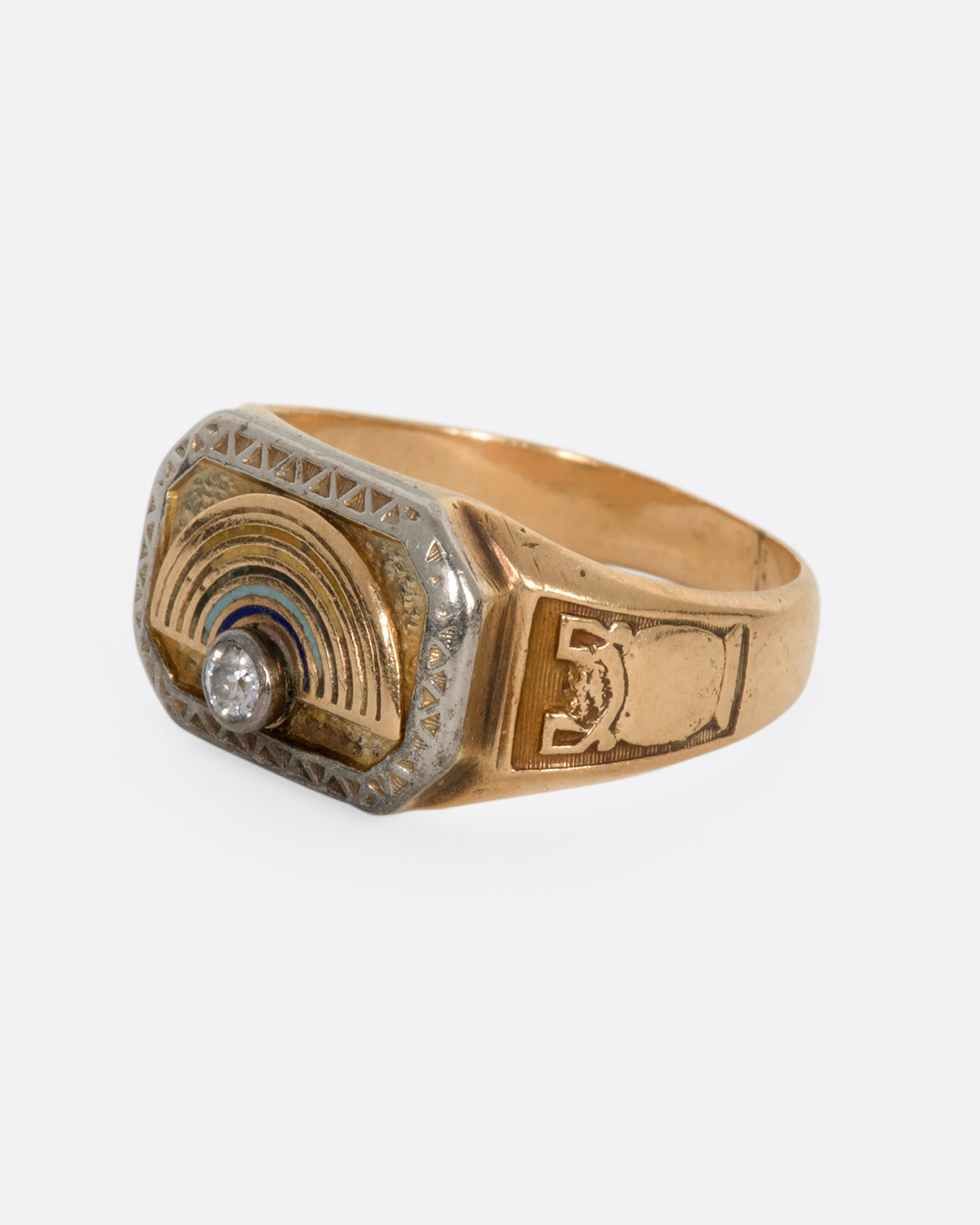 A yellow gold vintage signet ring with an arch and a round diamond on the front and a vase on the shoulder. View from the alternate side.