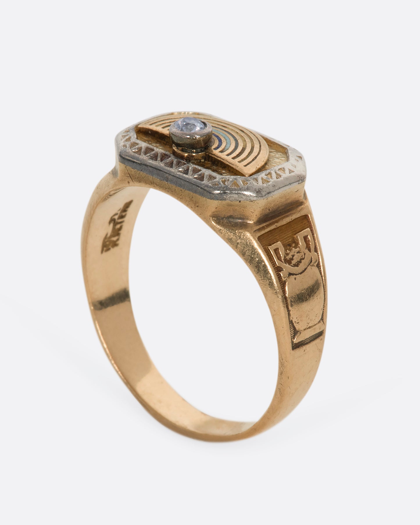 A yellow gold vintage signet ring with an arch and a round diamond on the front and a vase on the shoulder. View from the side standing up.