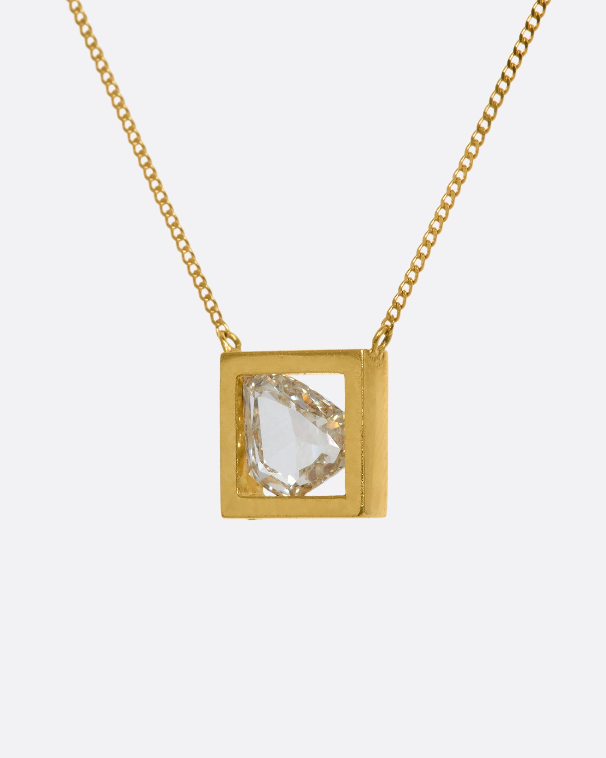 A yellow gold square fixed pendant frame holds a rose cut diamond slice hanging from a chain. View from the side.