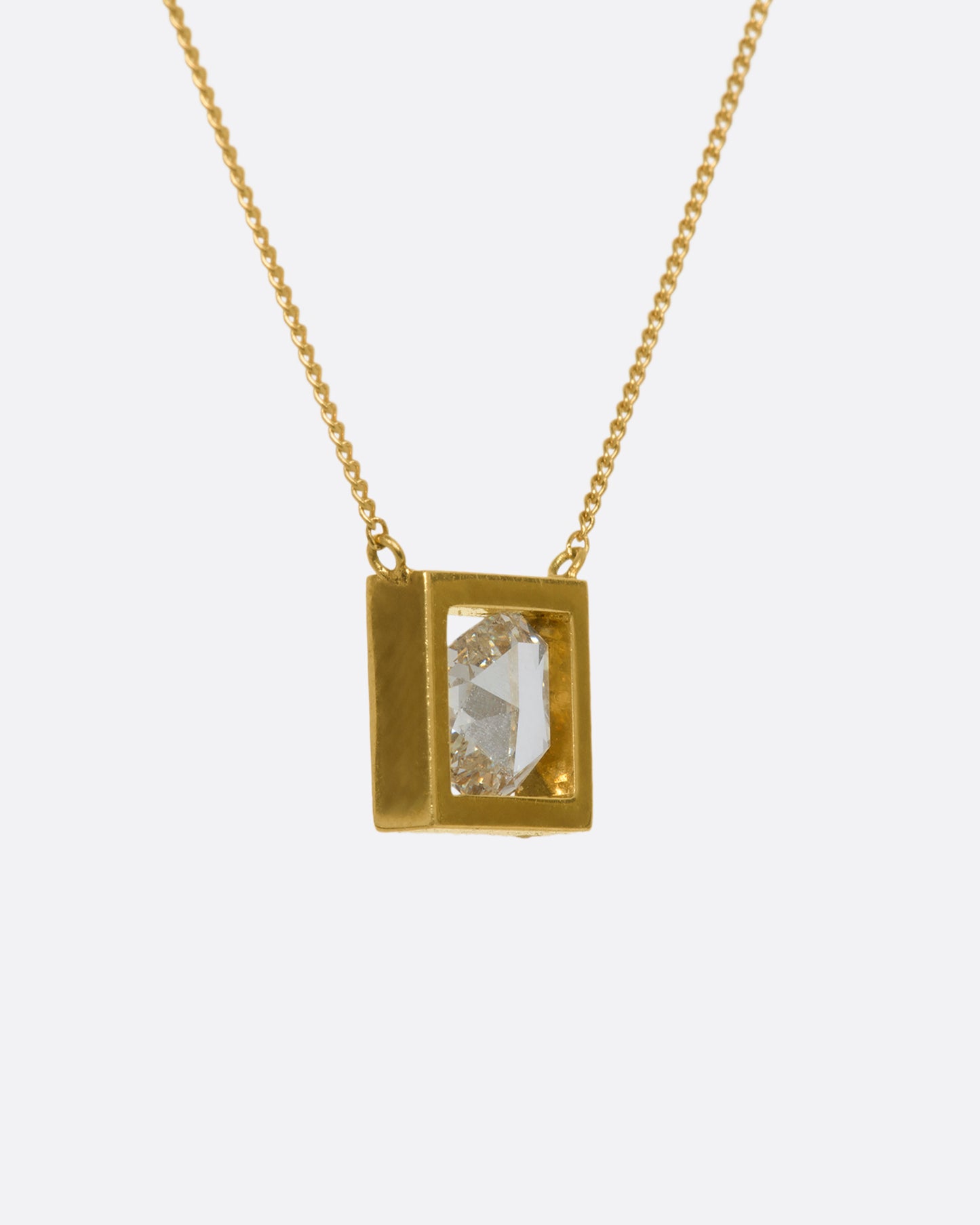 A yellow gold square fixed pendant frame holds a rose cut diamond slice hanging from a chain. View from the back.