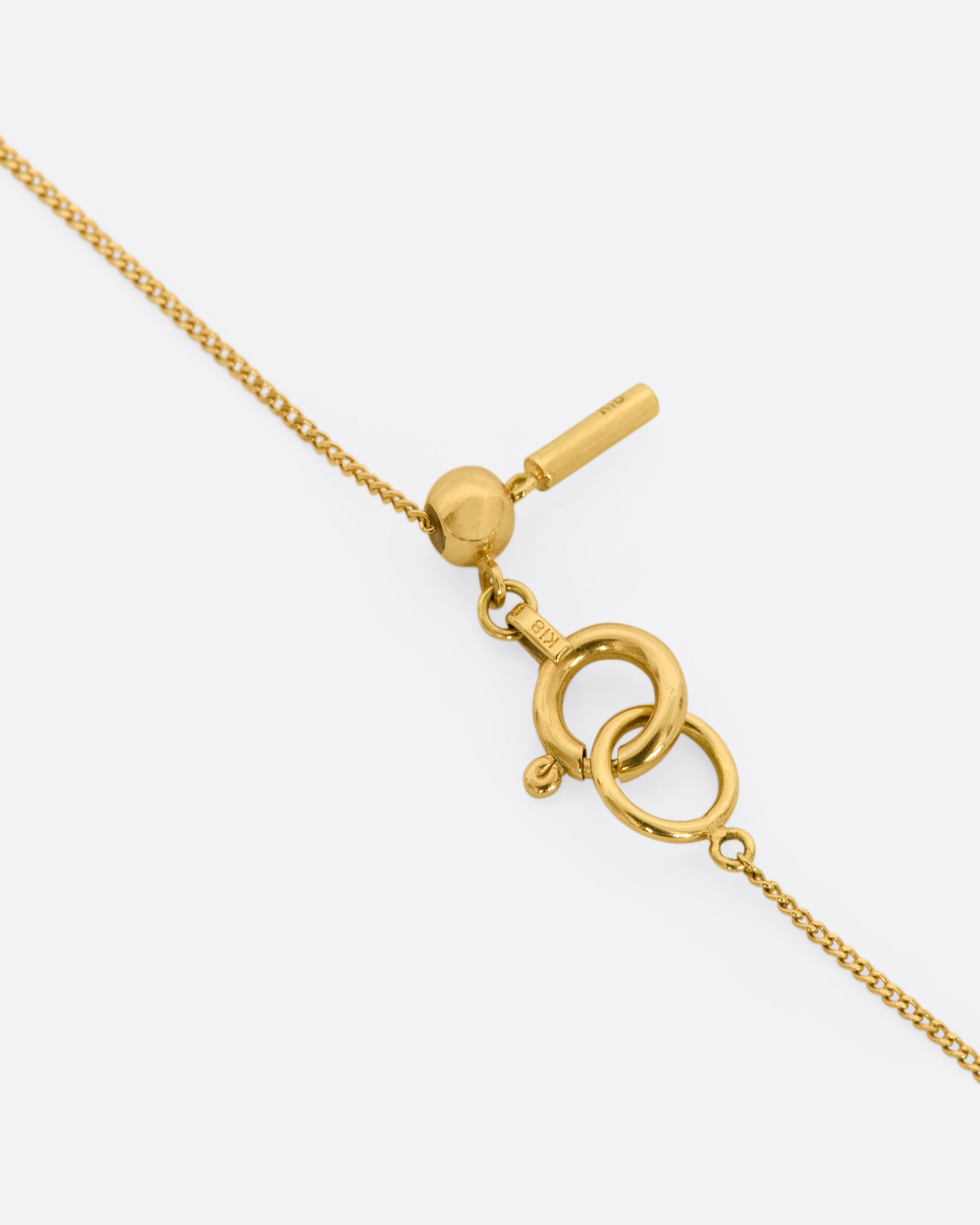 A brilliant marquise diamond throws sparkle from every angle as it hovers in an open, rich yellow gold fixed window. This minimalist setting is suspended from a fine yellow gold curb chain. View of the closure.