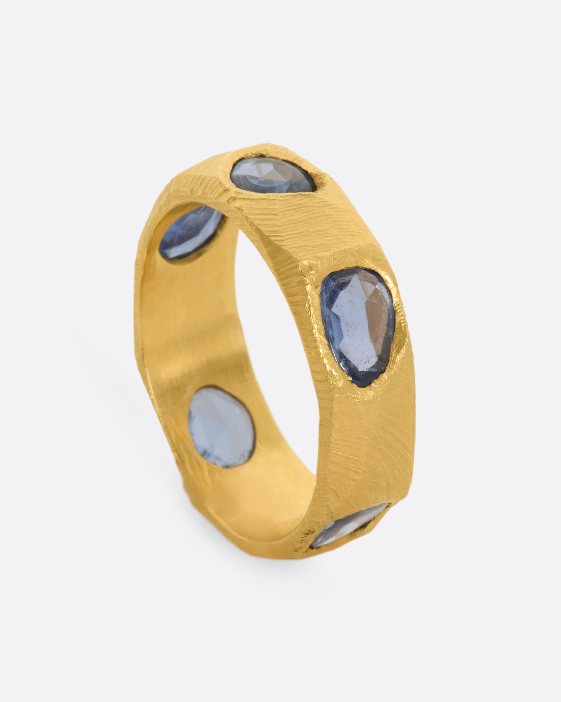 A yellow gold ring with five large blue rose cut sapphires. Shown from the side, standing up.