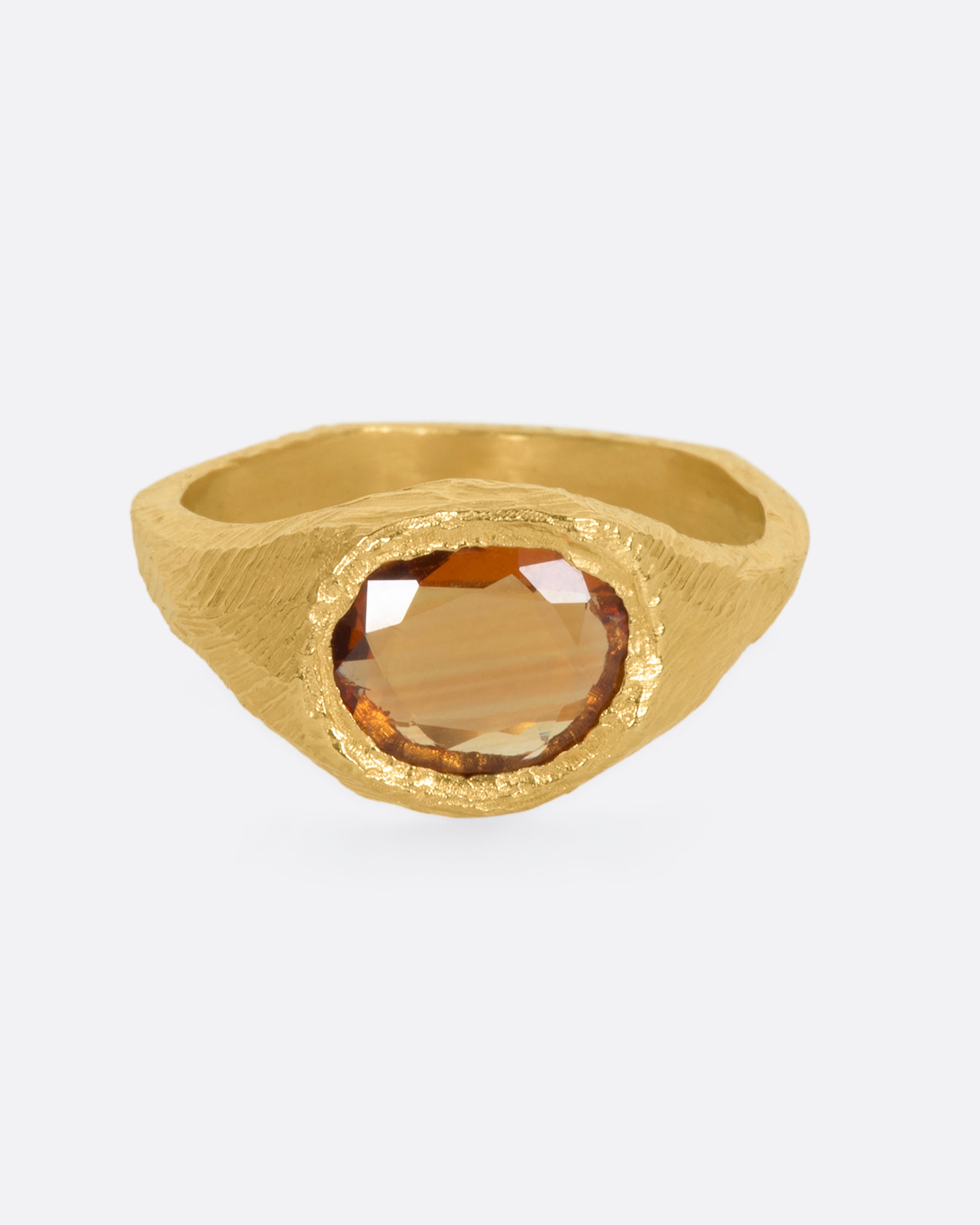 A hand carved yellow gold ring with an orange sapphire. View from the front.