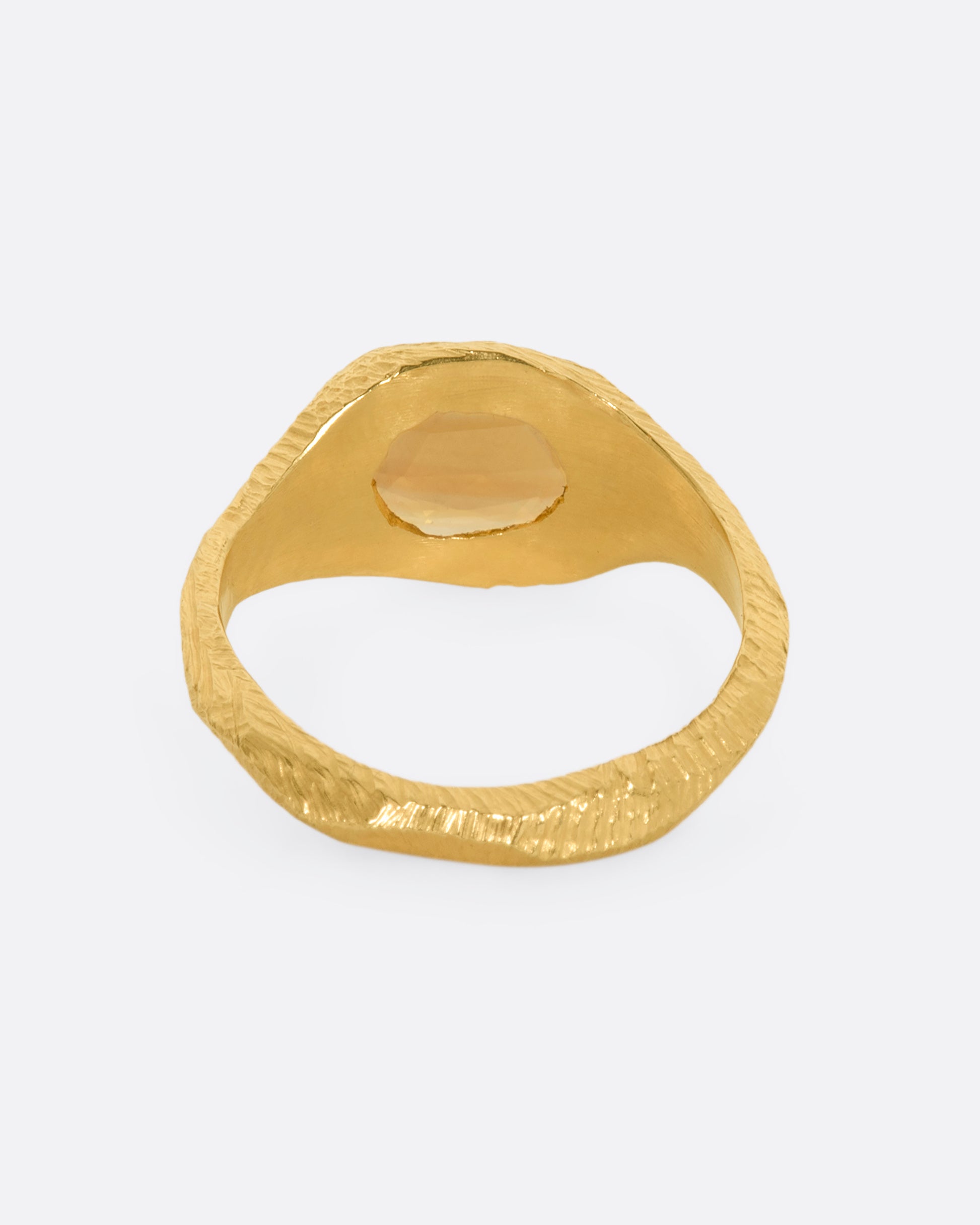 A hand carved yellow gold ring with an orange sapphire. View from the back.