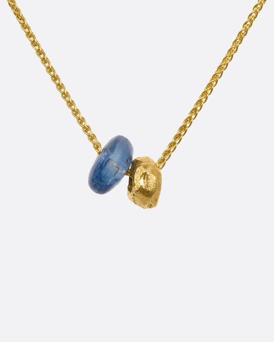 A kyanite bead and gold textured bead hang from a yellow gold chain. View up close of the beads.