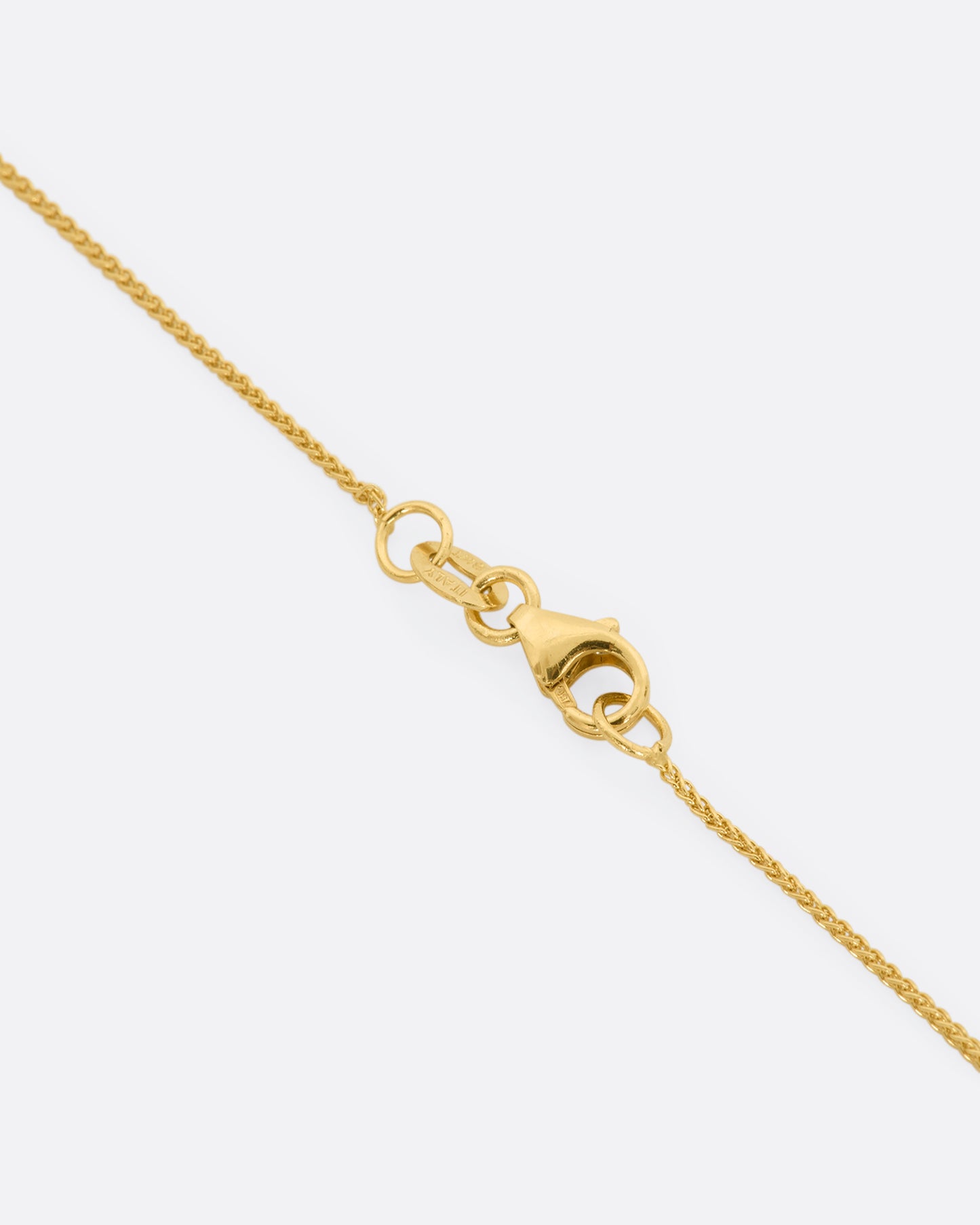 A hand carved textured yellow gold pendant holds a cut sapphire solitaire hanging from a yellow gold chain. View up close of the closure.