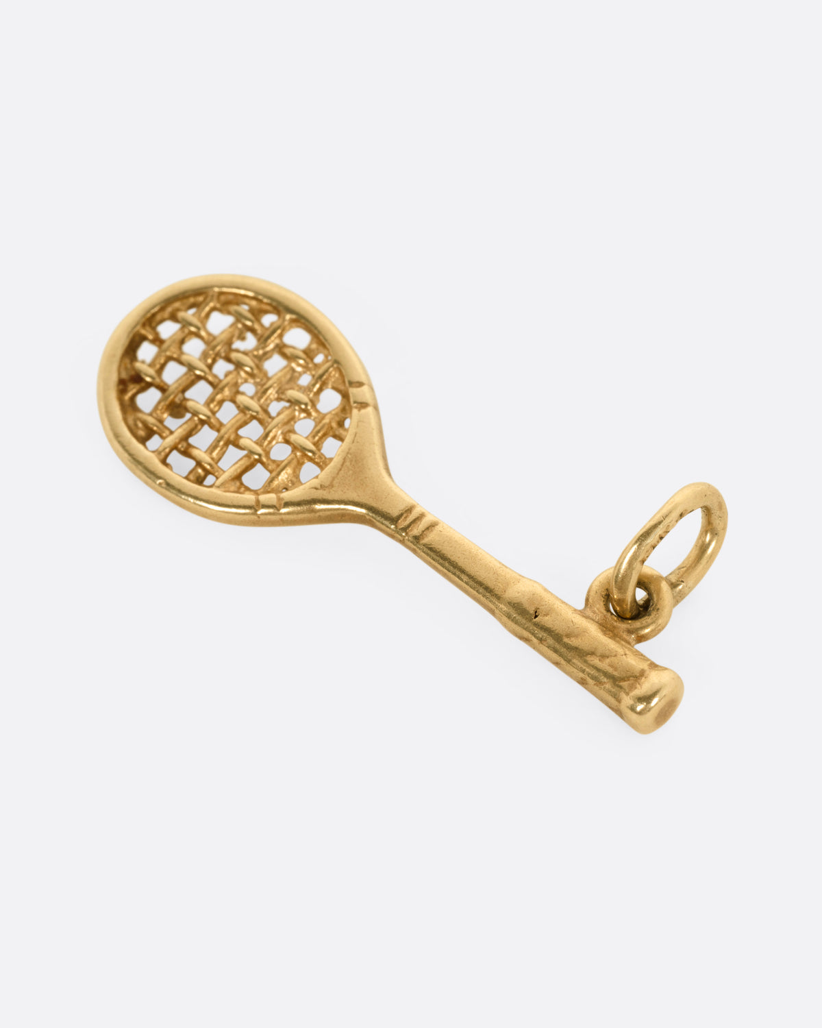 A gold tennis racket pendant charm with a woven string design, shown from above, laying flat. 