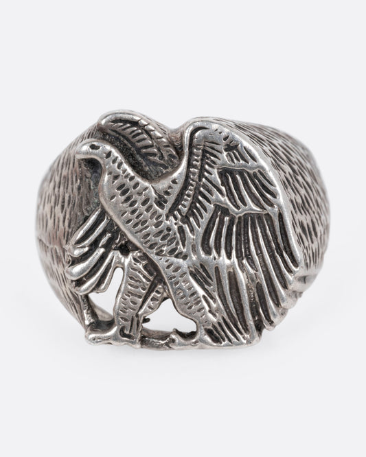 A silver signet ring with a textured eagle design, shown from the front.