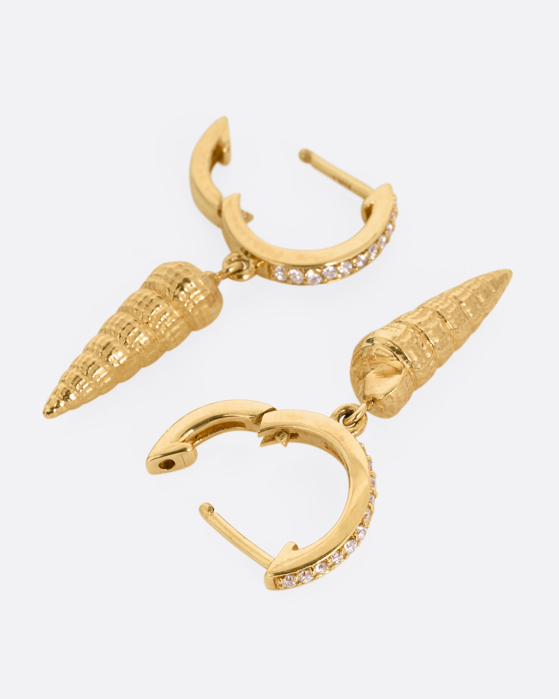 A pair of yellow gold diamond lined hoop earrings with seashell drops. Shown open from the front.