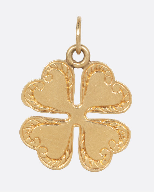A yellow gold four leaf clover charm with engraved edges. Shown from the front.