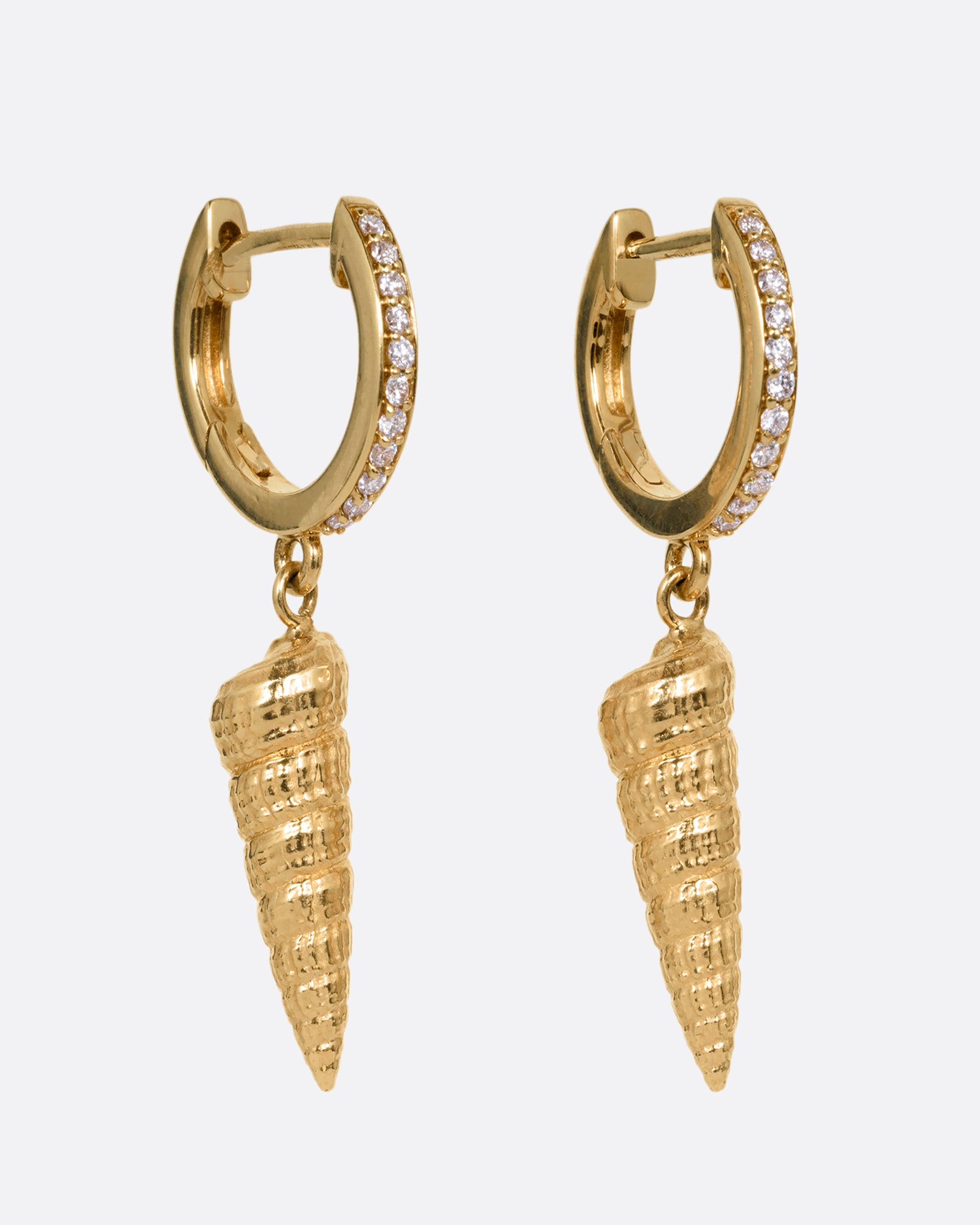 A pair of yellow gold diamond lined hoop earrings with seashell drops. Shown from the side.