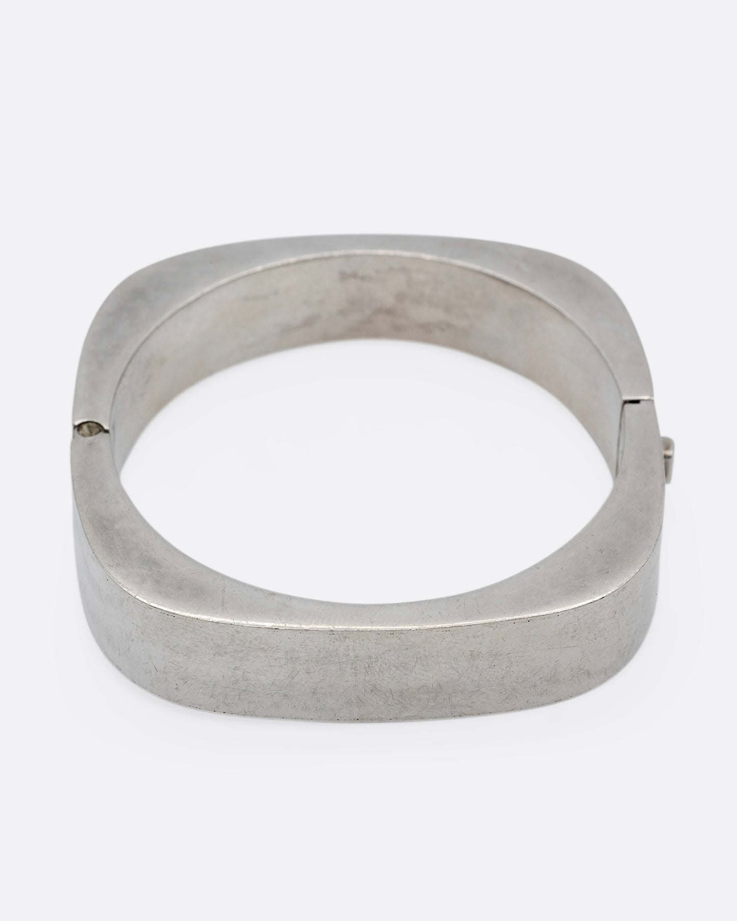 A thick square silver bracelet with a hinge and clasp. Shown from the front.