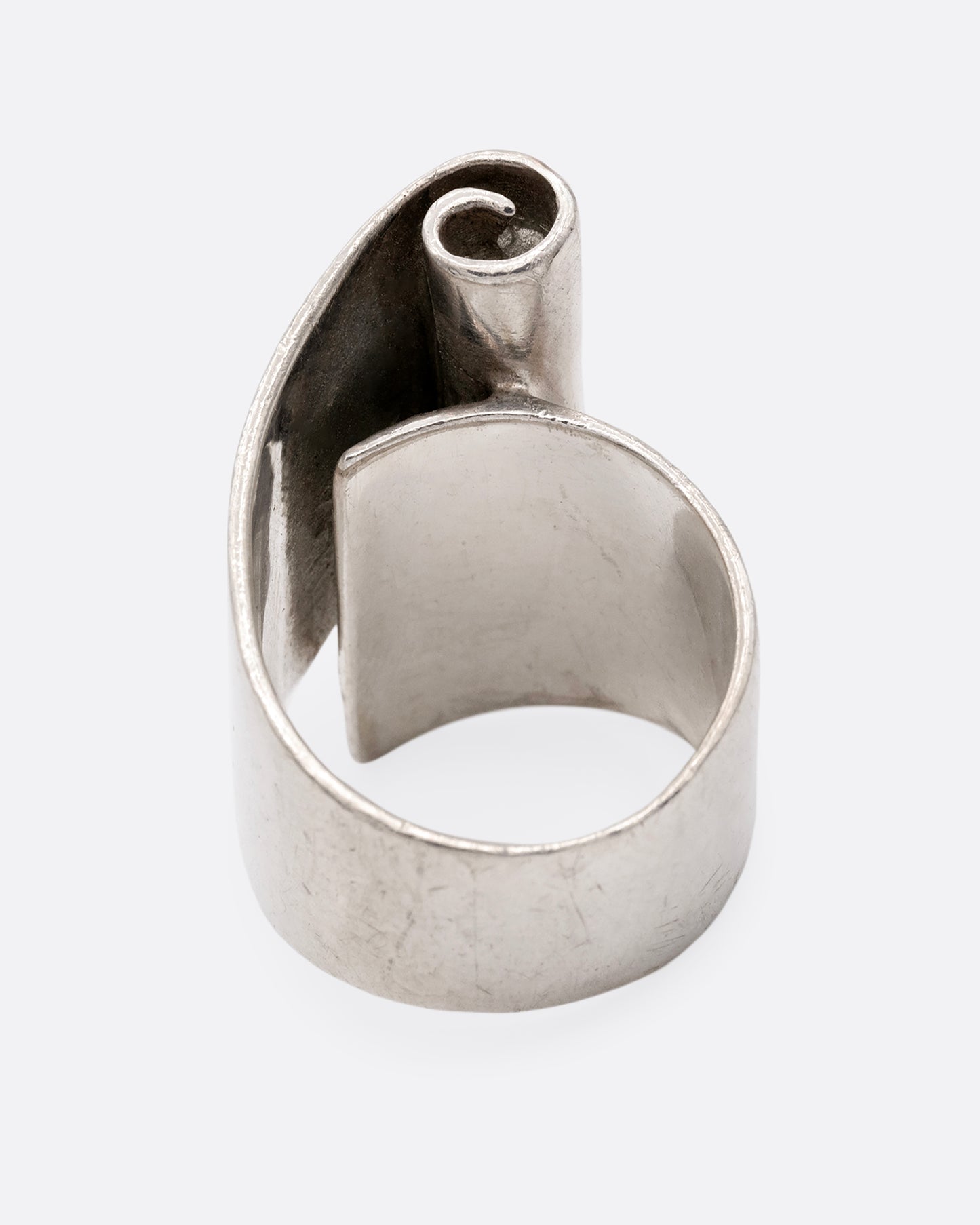 A silver ring with a scroll on its face. Shown from the back.