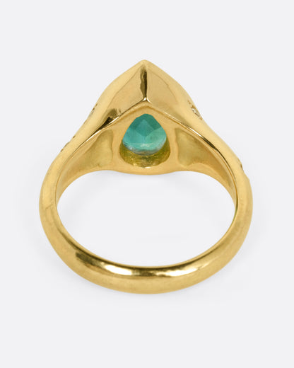 A yellow gold ring with a Zambian emerald accented by scattered diamonds, shown from the back.