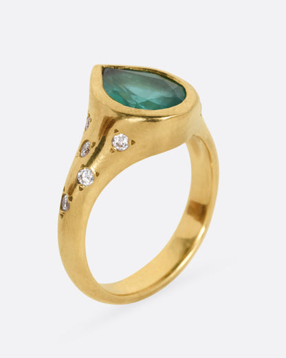 A yellow gold ring with a Zambian emerald accented by scattered diamonds, shown from the side standing up.