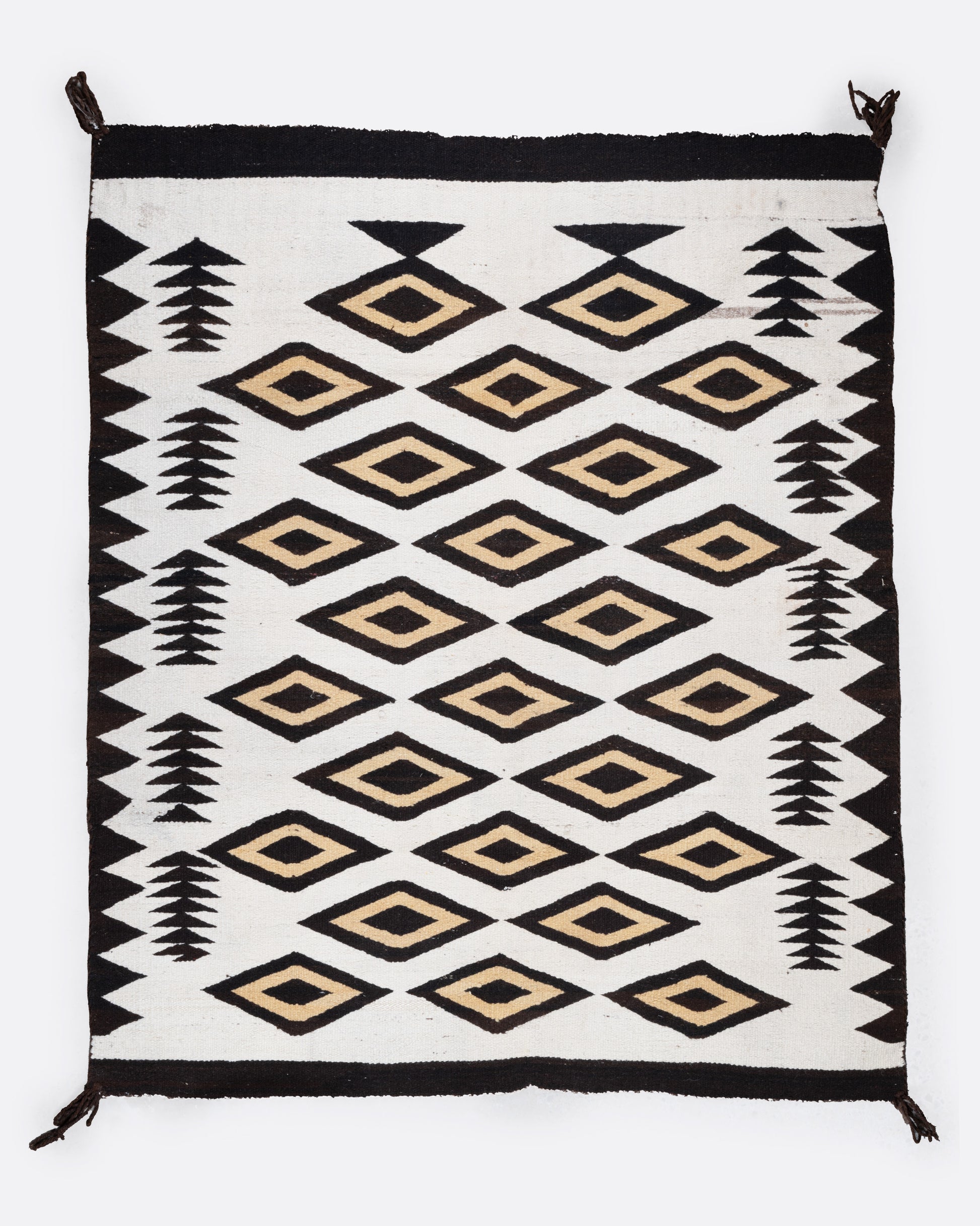 A bird's eye view of a white, black, and yellow Navajo Crystal weaving rug with a bold border and stacked diamond pattern.
