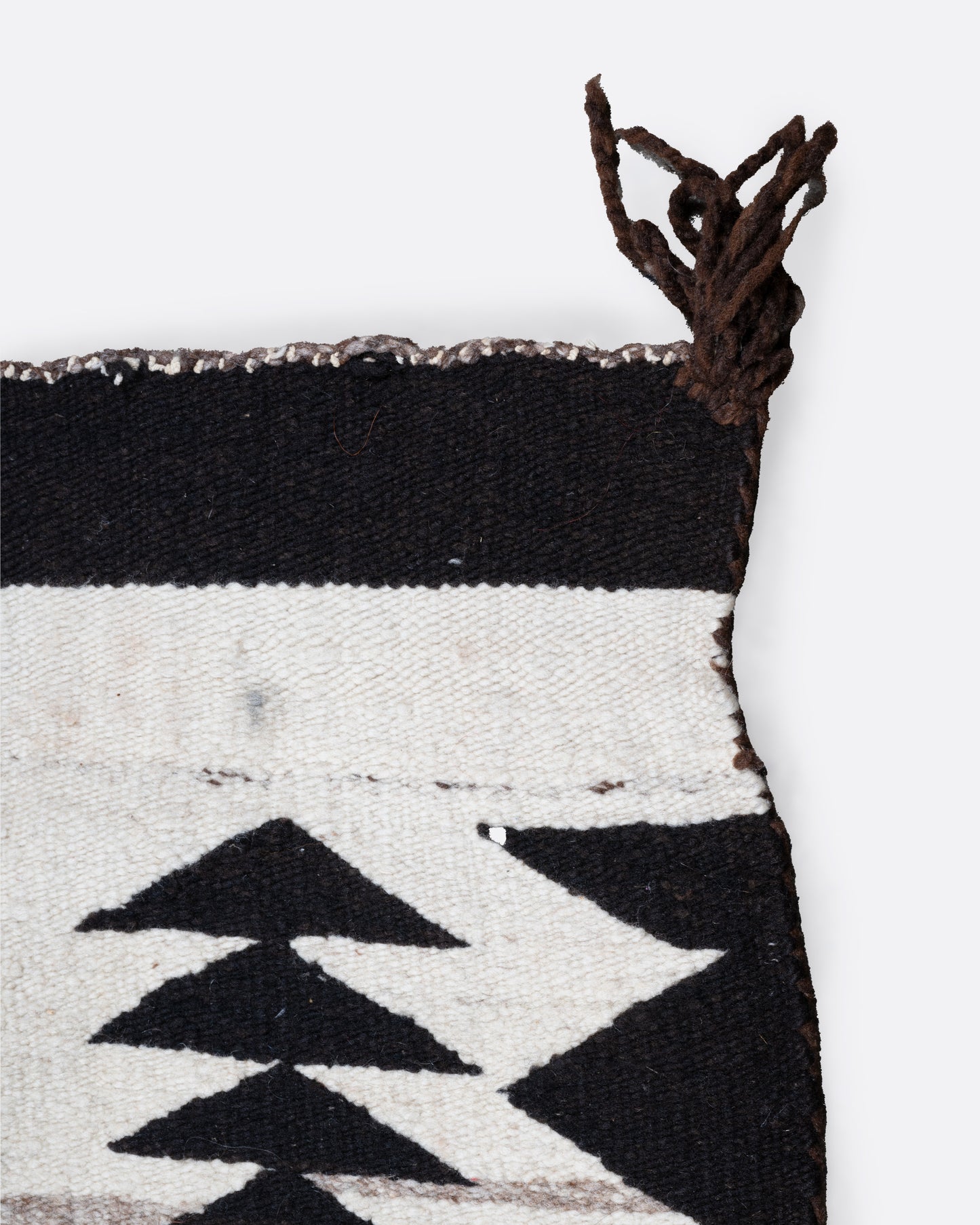 A close up of a white, black, and yellow Navajo Crystal weaving rug with a bold border and stacked diamond pattern.