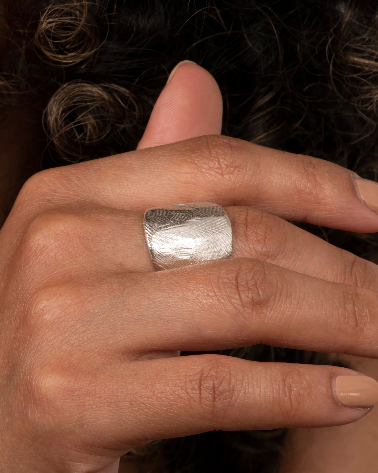 Textured sterling silver wide band ring. View on a hand.