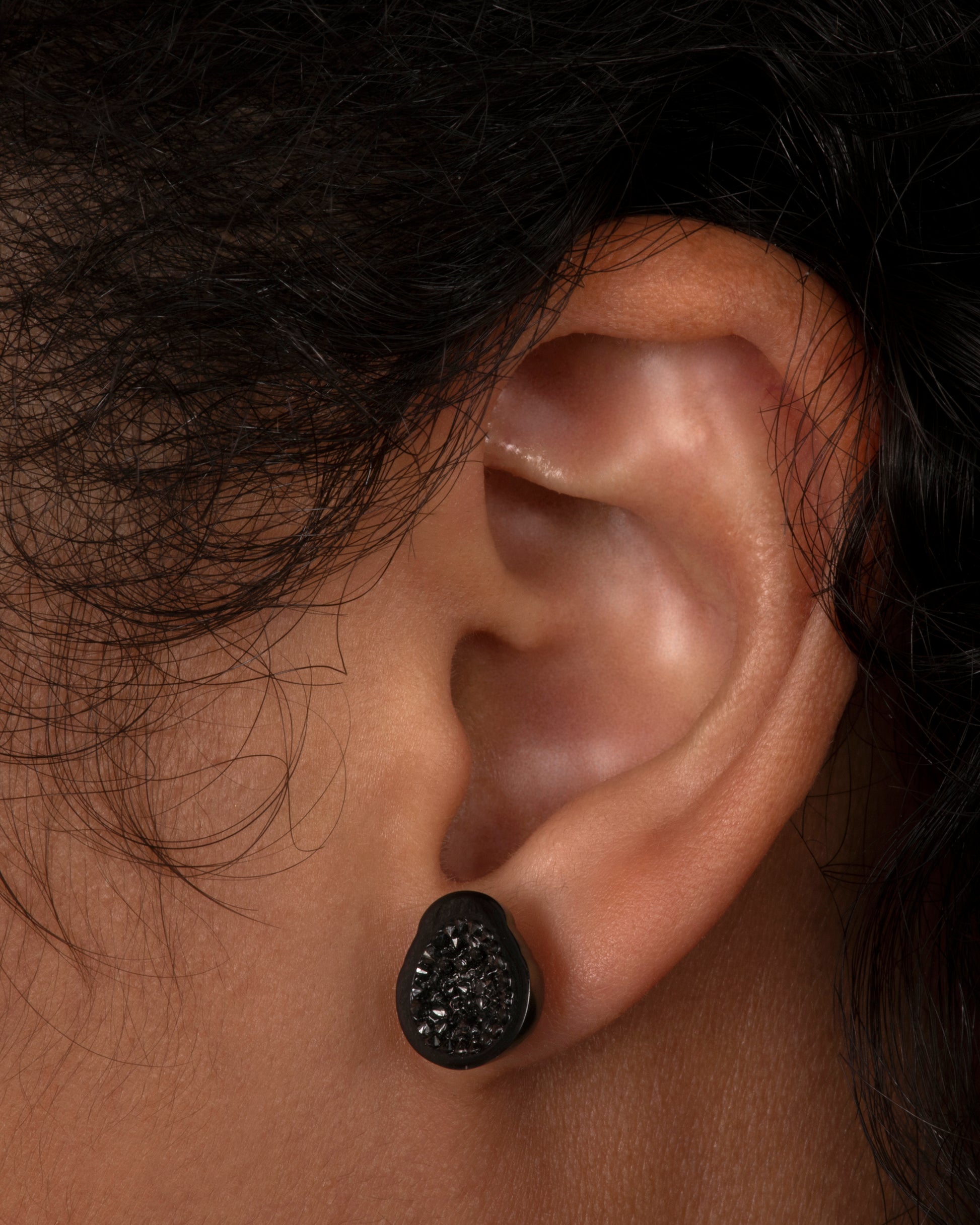 White gold stud earrings with black diamond lined Tahitian pearls. View on an ear.