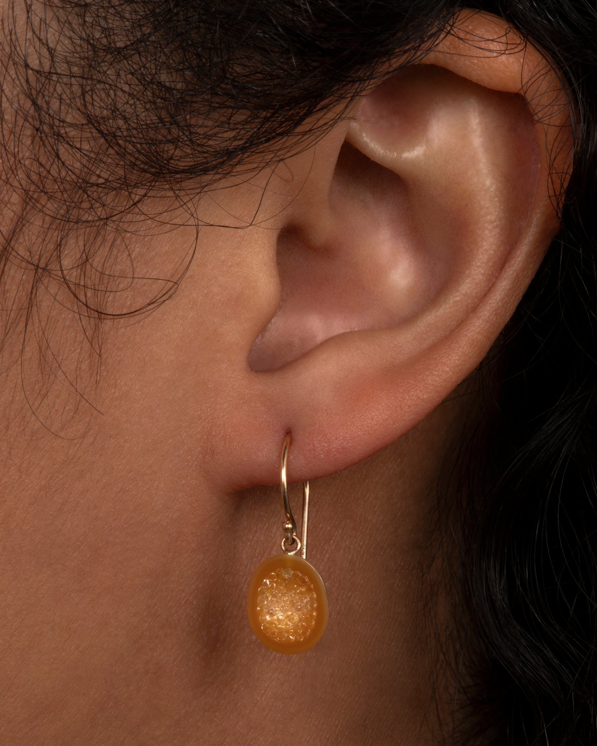 Yellow gold earrings with sapphire lined pearl drops. View on an ear.