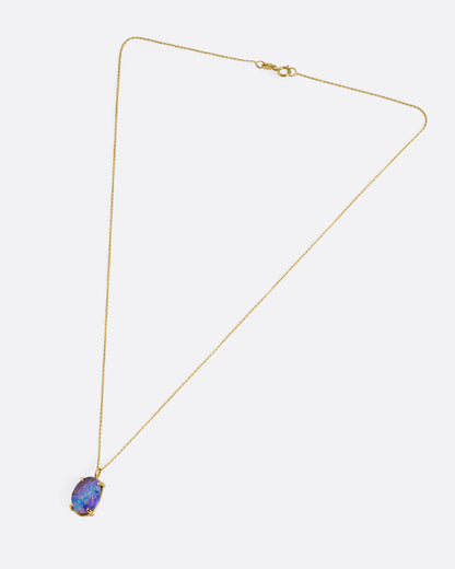 A yellow gold cable chain necklace with a prong set boulder opal pendant, shown from the front.