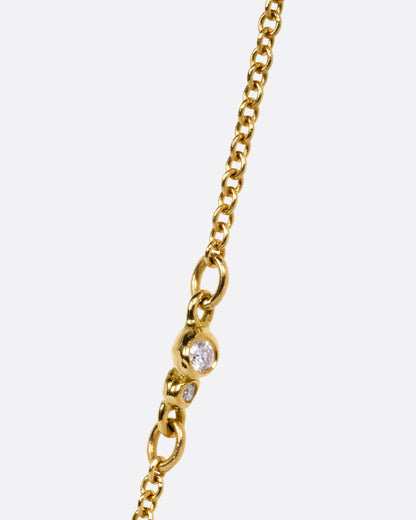 A close up of a diamond accented yellow gold cable chain.