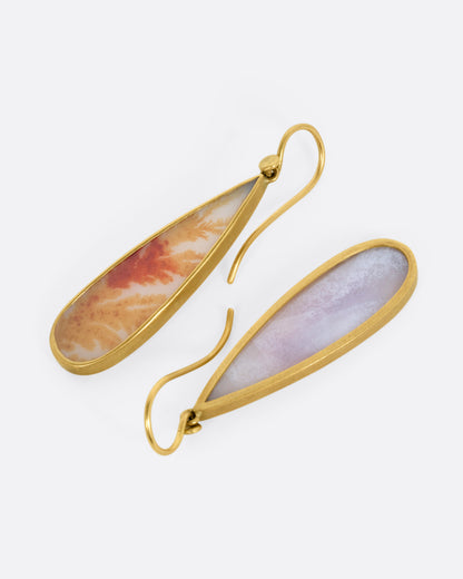 A pair of pear shaped dendritic agate drops in 18K gold bezel settings. One earring is shown from the front, the other from the back.