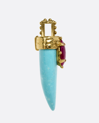 A yellow gold pendant with a sleeping beauty turquoise horn and a marquise ruby, shown from the side.