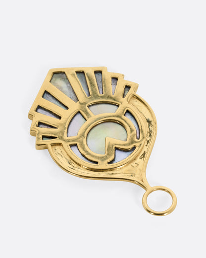 A yellow gold pendant with a feathery plumage design  inlaid with mother of pearl, shown from the back.