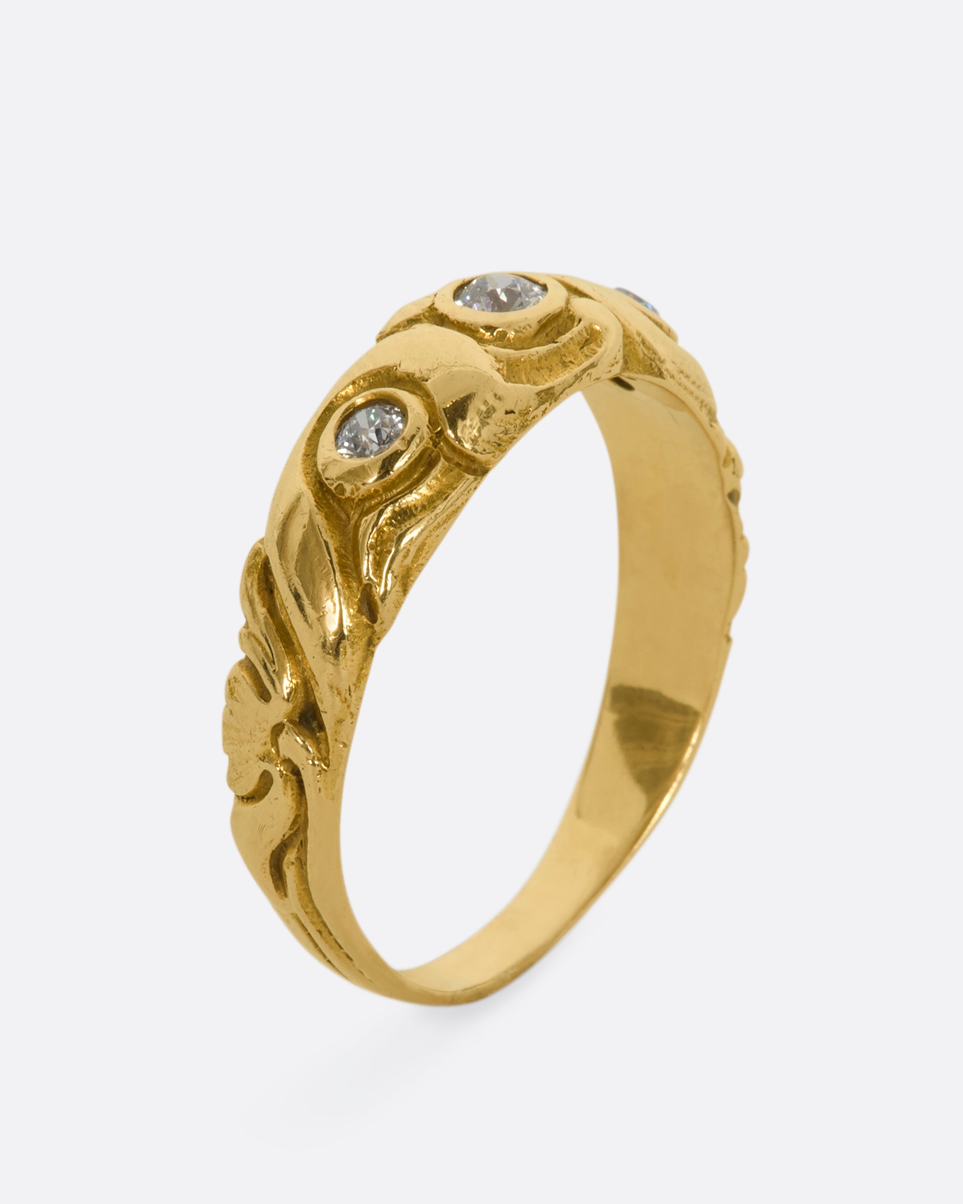 A textured yellow gold ring with three diamonds. View from the side, standing up.