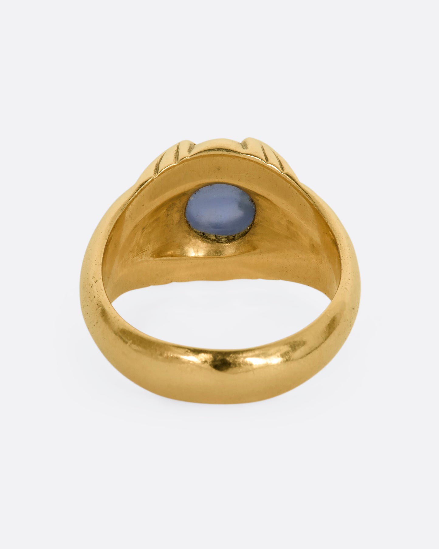 A yellow gold ring with a prong set star sapphire. View from the back.