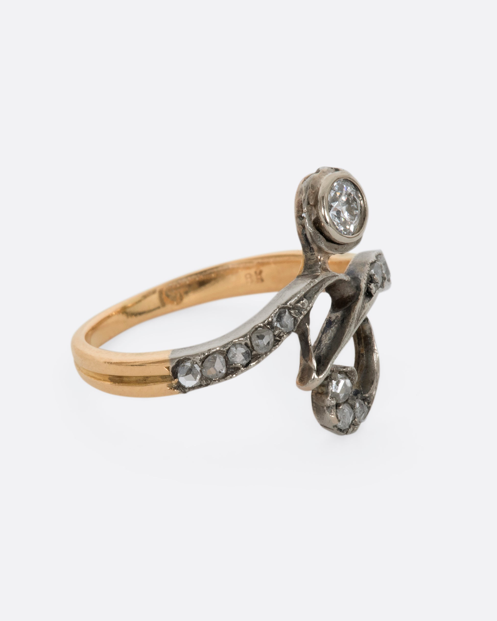 A white and rose gold diamond encrusted abstract ring. View from the side. 