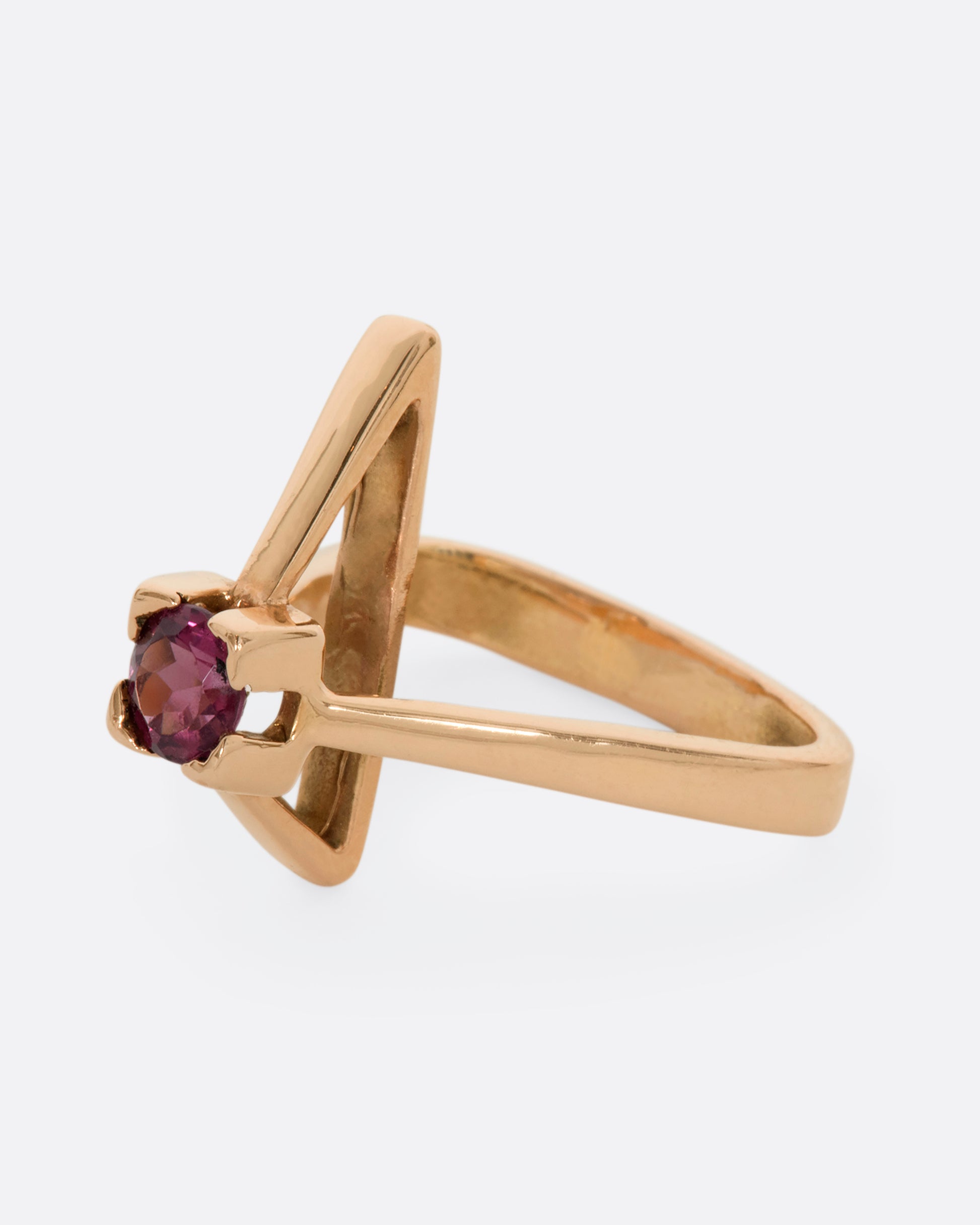 A geometric rose gold ring with a prong set pink tourmaline. Shown from the side.