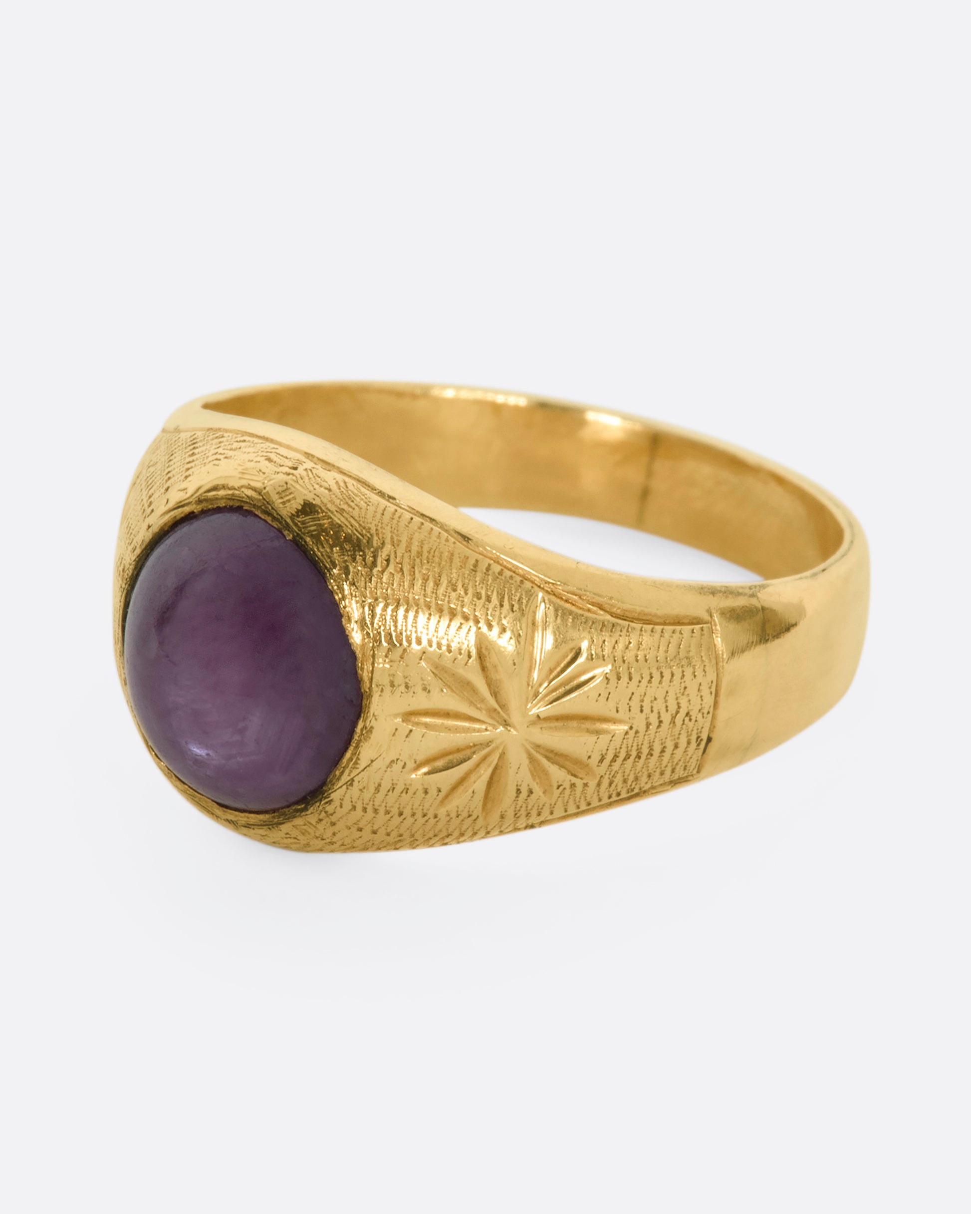 A domed yellow gold vintage ring with a ruby cabochon and starflower details. View from the side.