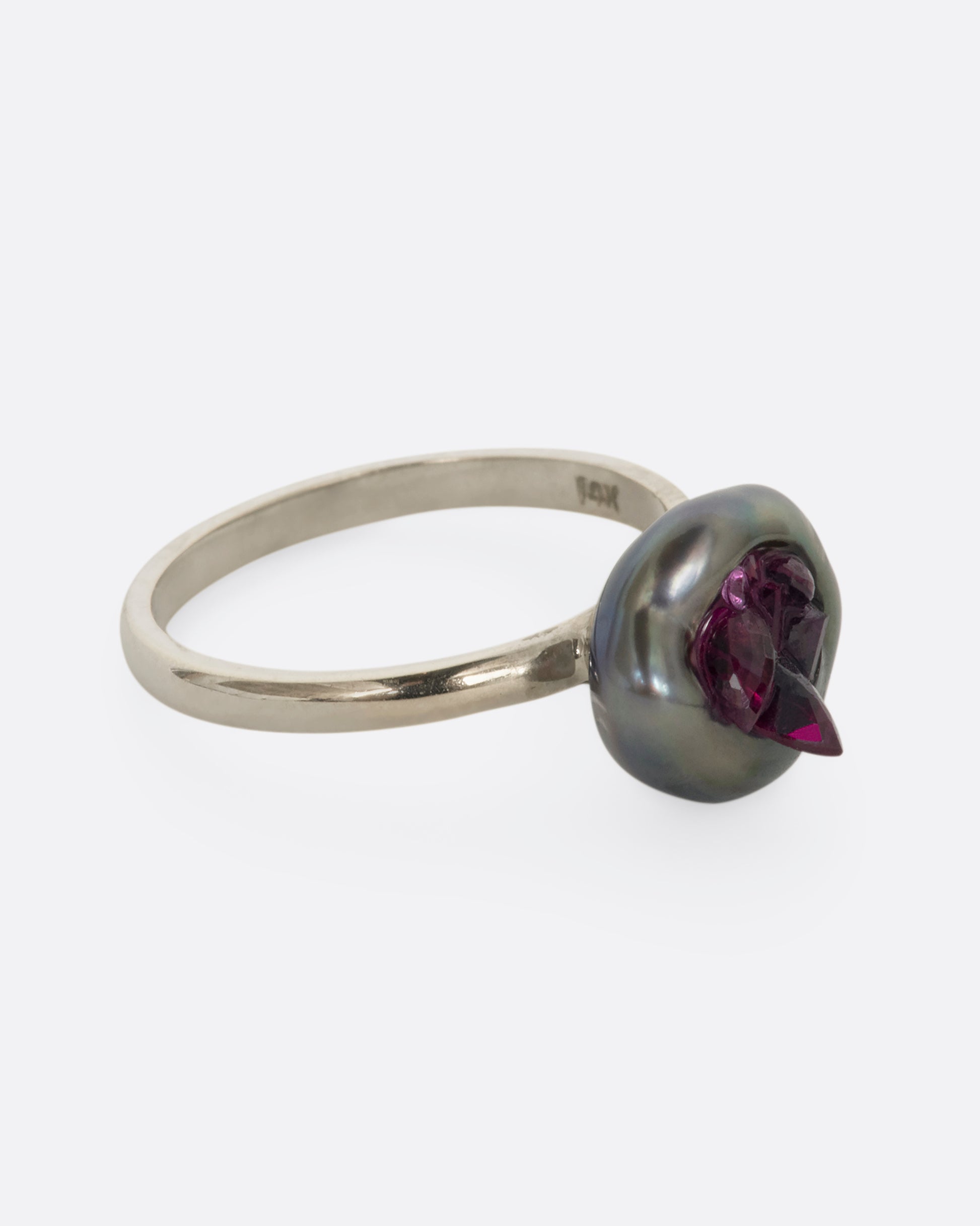 A white gold ring with carved Tahitian Keshi pearl lined with reclaimed rubies. View straight on from the alternate side.