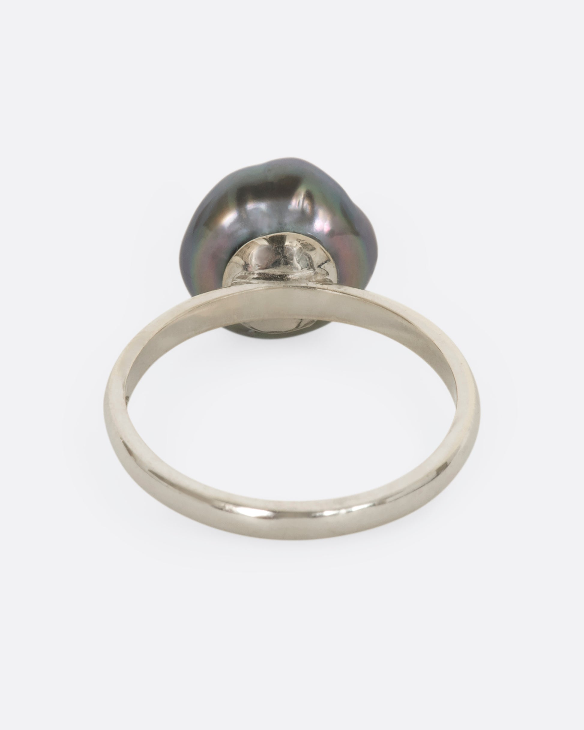 A white gold ring with carved Tahitian Keshi pearl lined with reclaimed rubies. View from the back.
