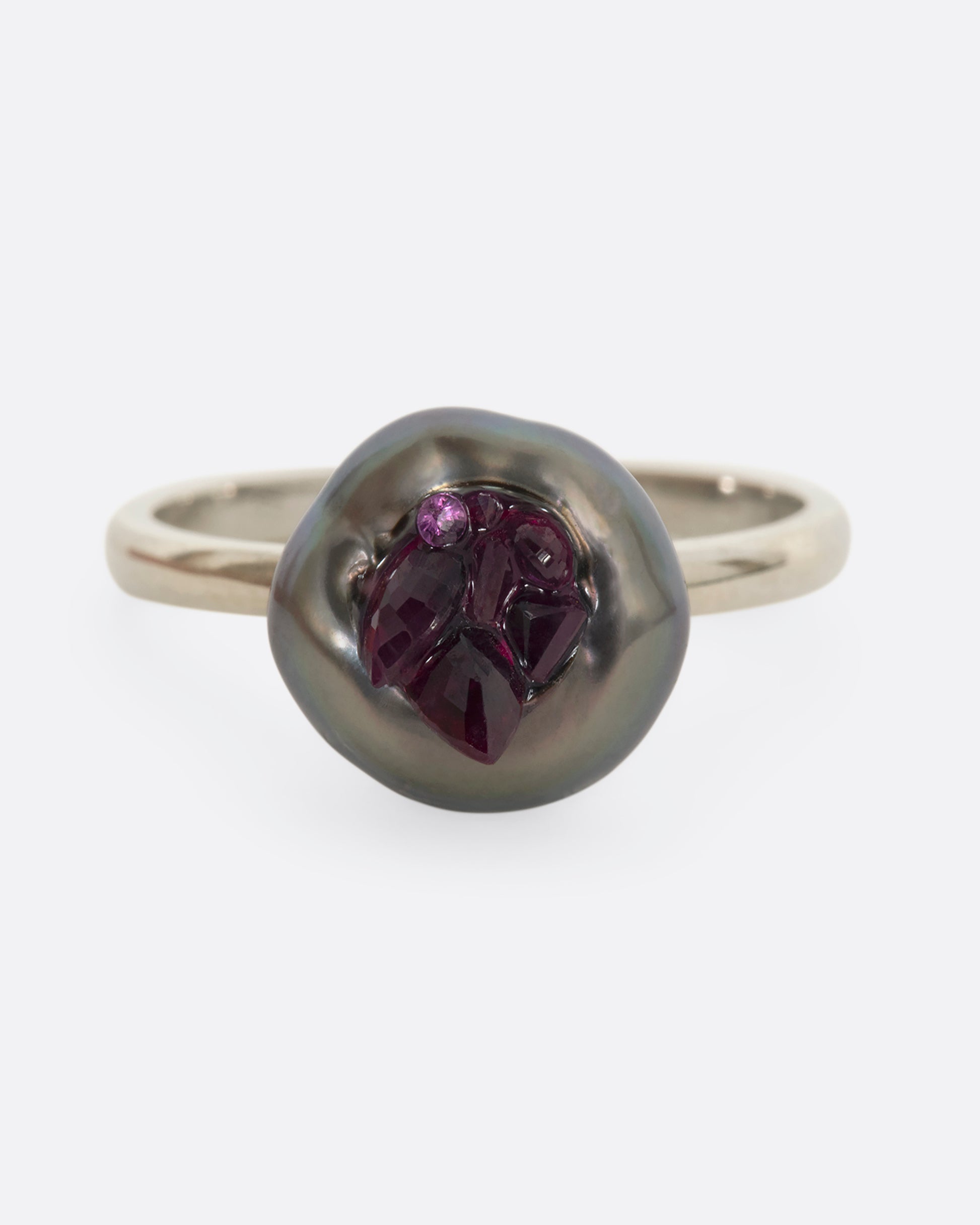 A white gold ring with carved Tahitian Keshi pearl lined with reclaimed rubies. View straight on from the front.