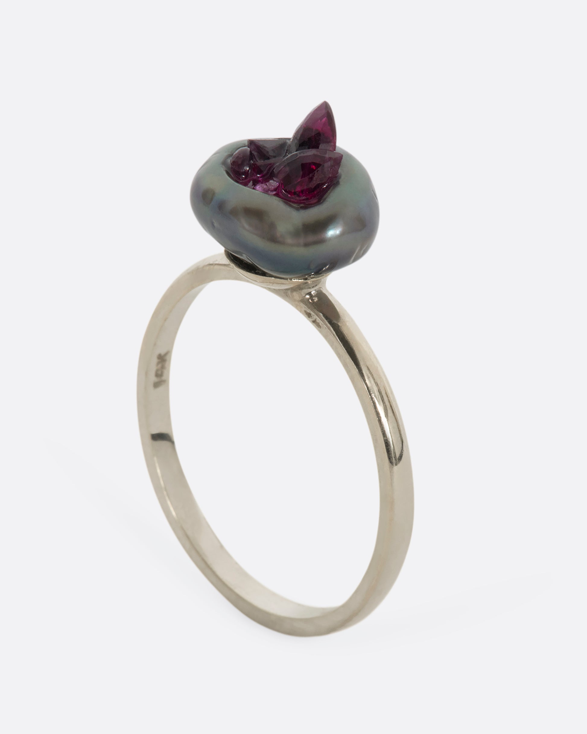 A white gold ring with carved Tahitian Keshi pearl lined with reclaimed rubies. View from the side standing up.